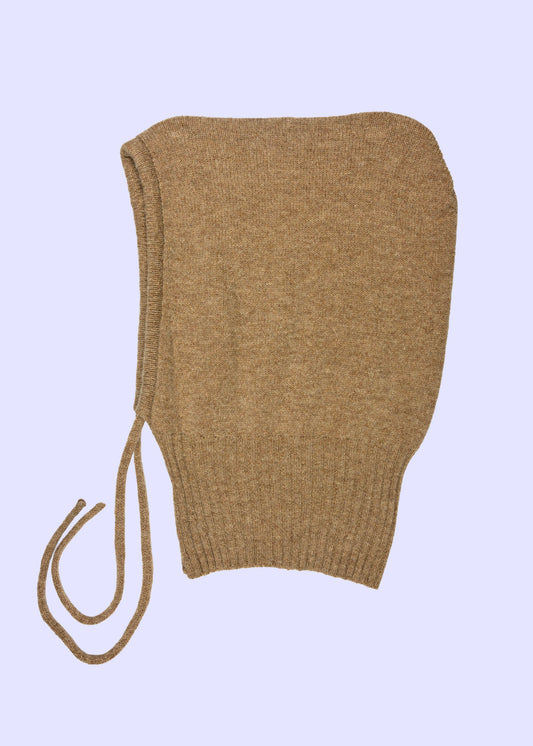 tan knitted bonnet on a light purple background
