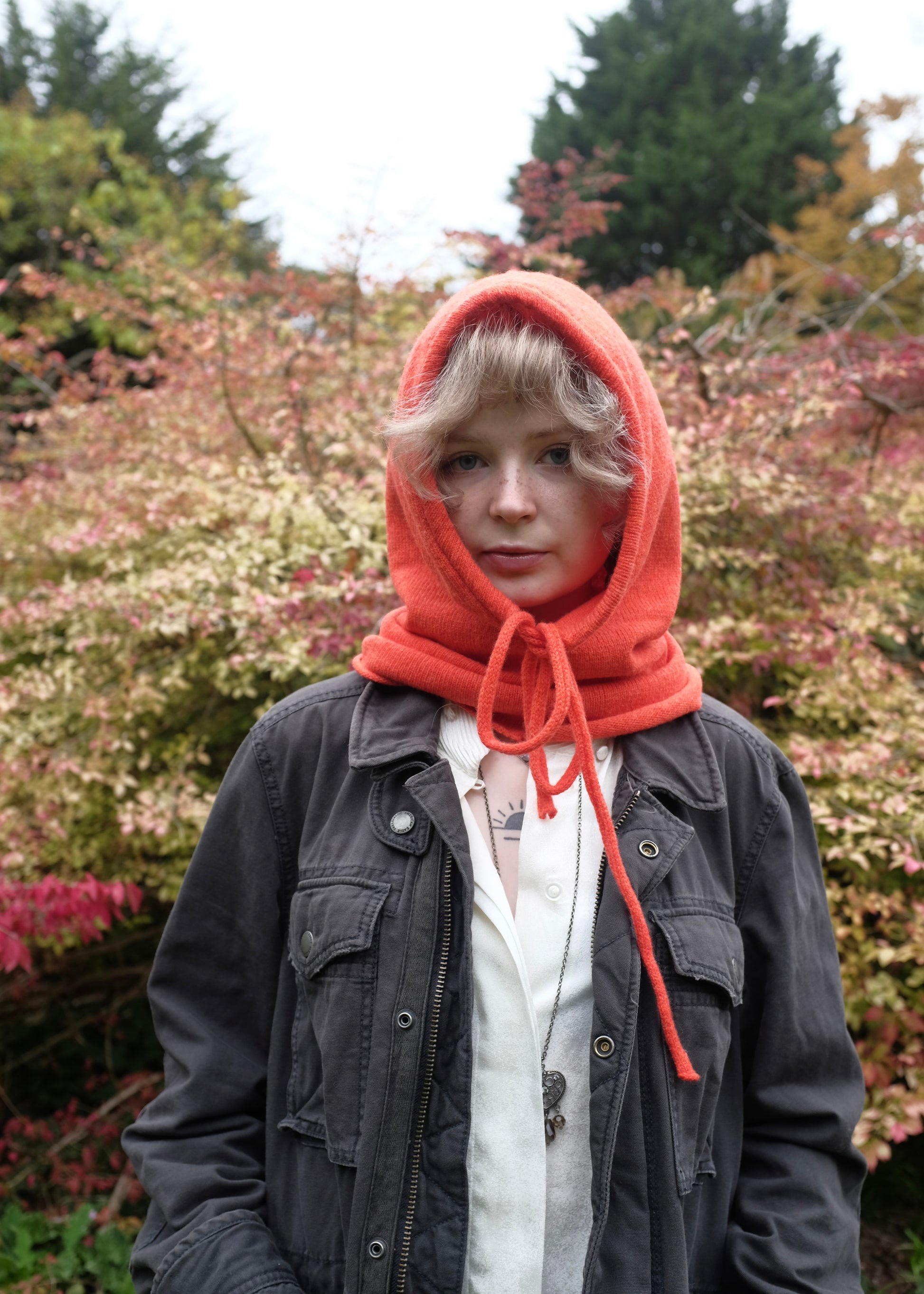 Our cashmere knitted balaclava in orange pictured on a woman outdoors 