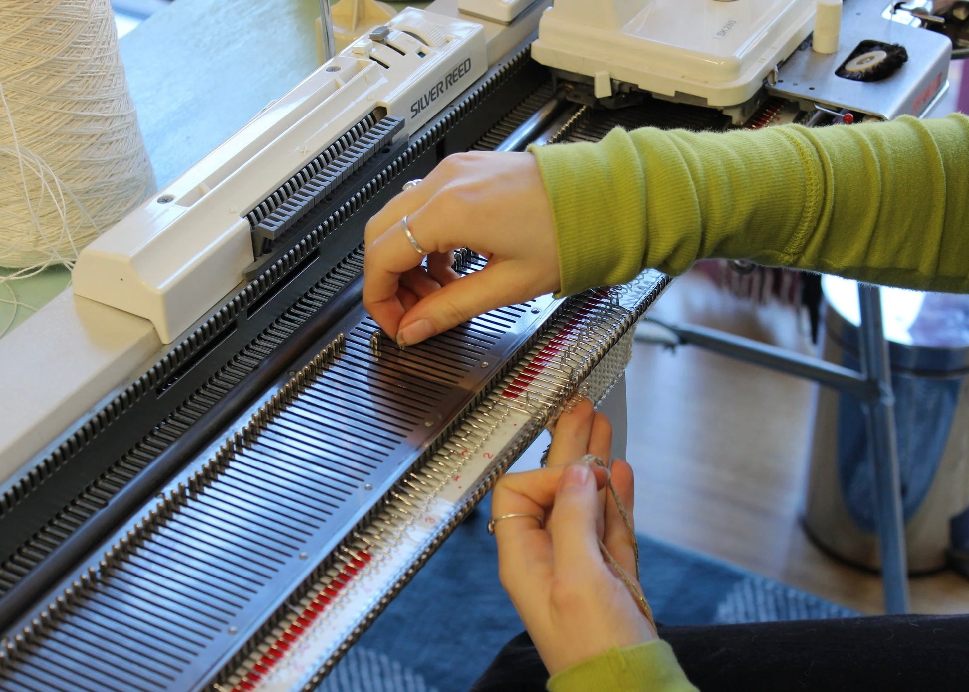 Person using a knitting machine with a focus on hands and equipment