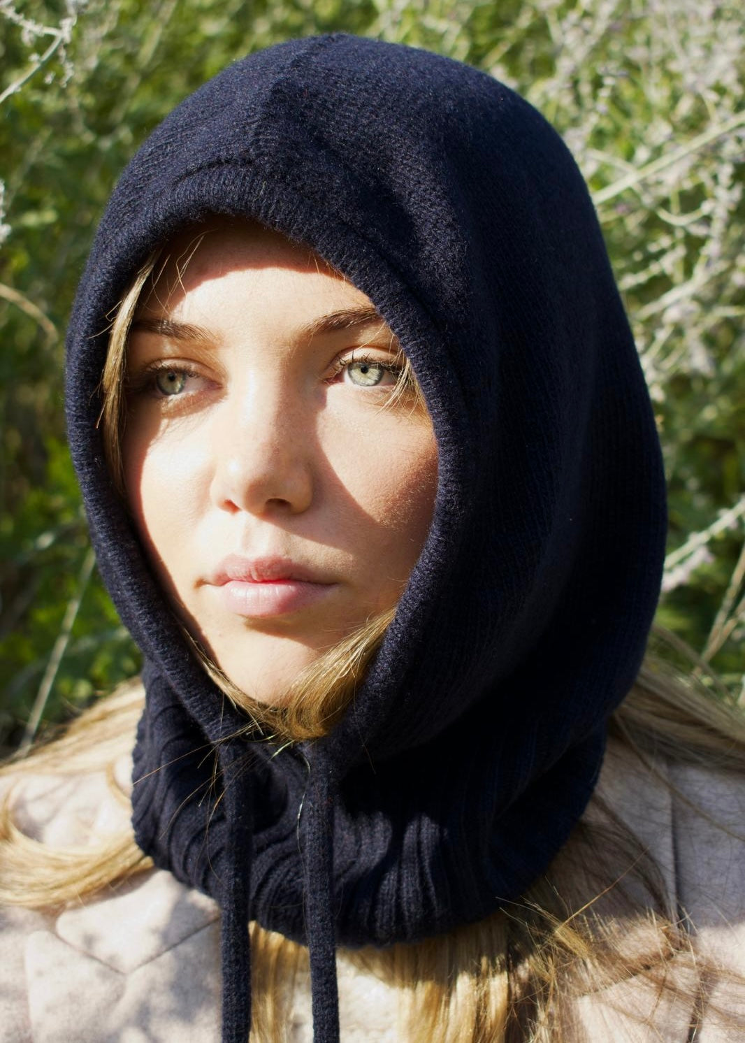 Our cashmere knitted balaclava hood in navy pictured on a woman outdoors 