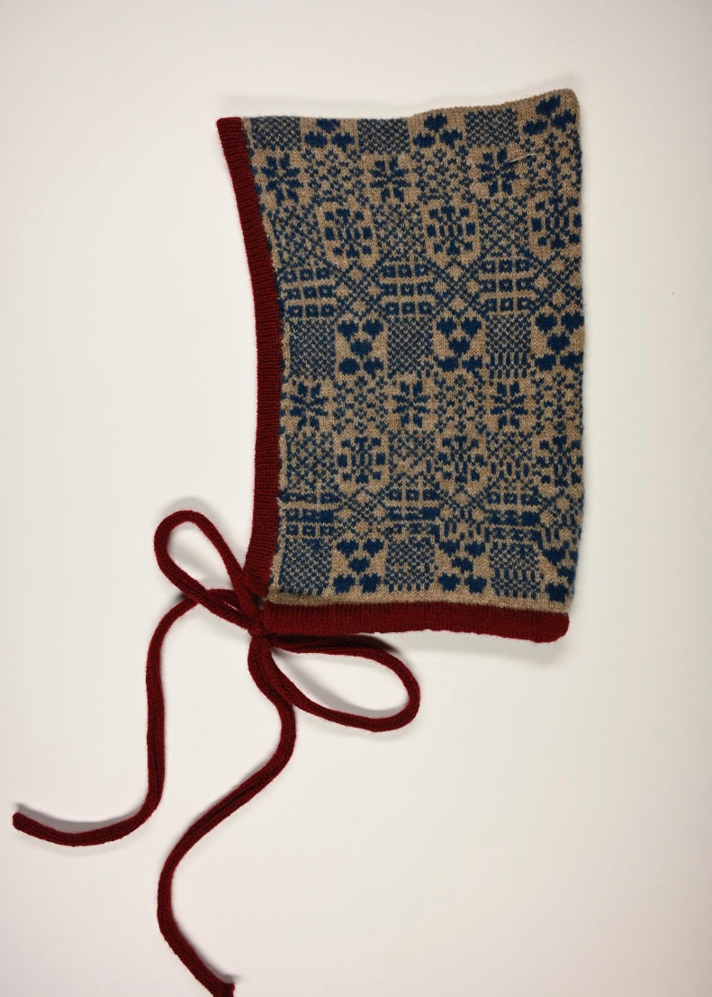 Red and beige Knitted bonnet with a fair isle blue patterned design on a white background