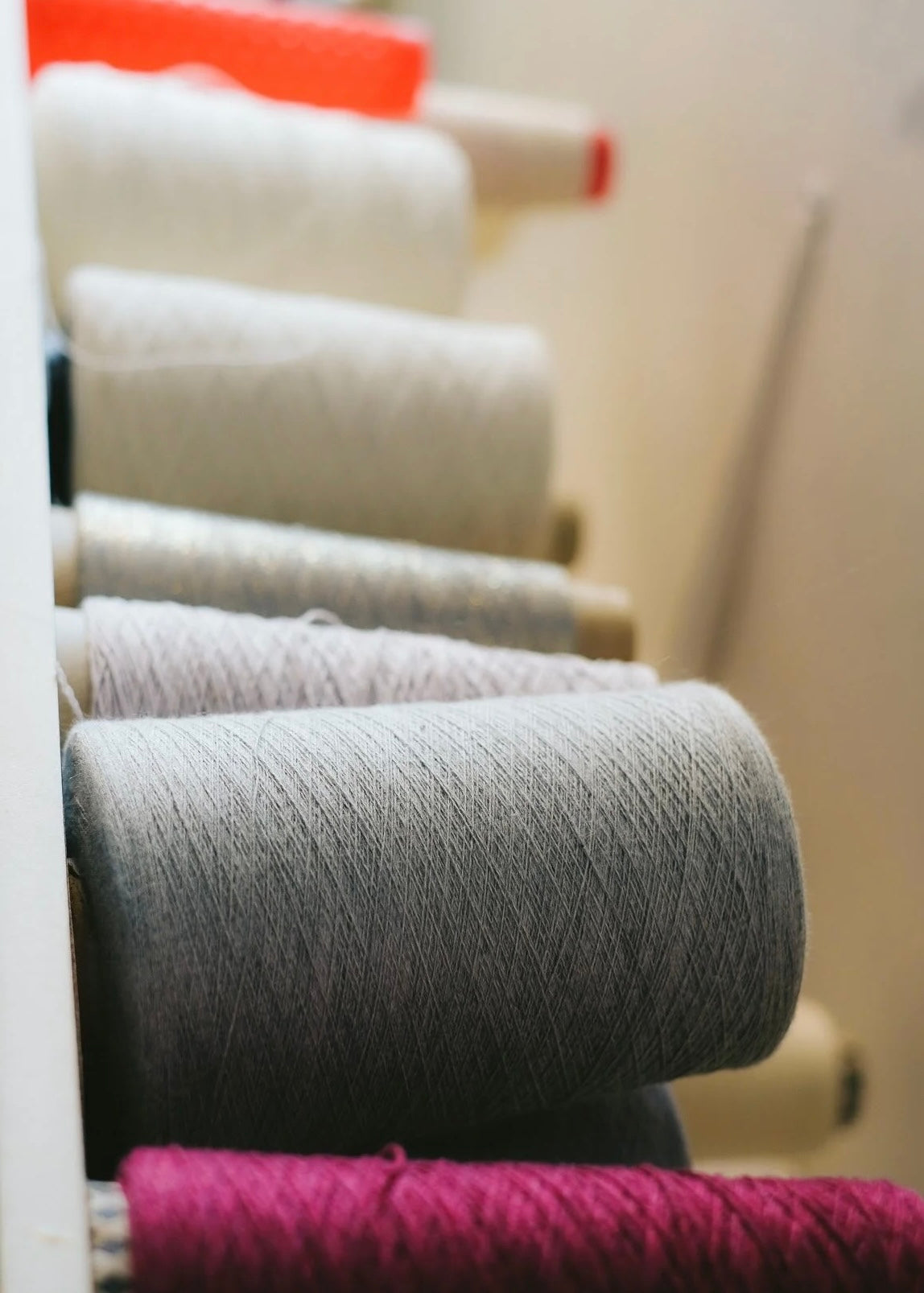 Spools of yarn in various colors on a rack