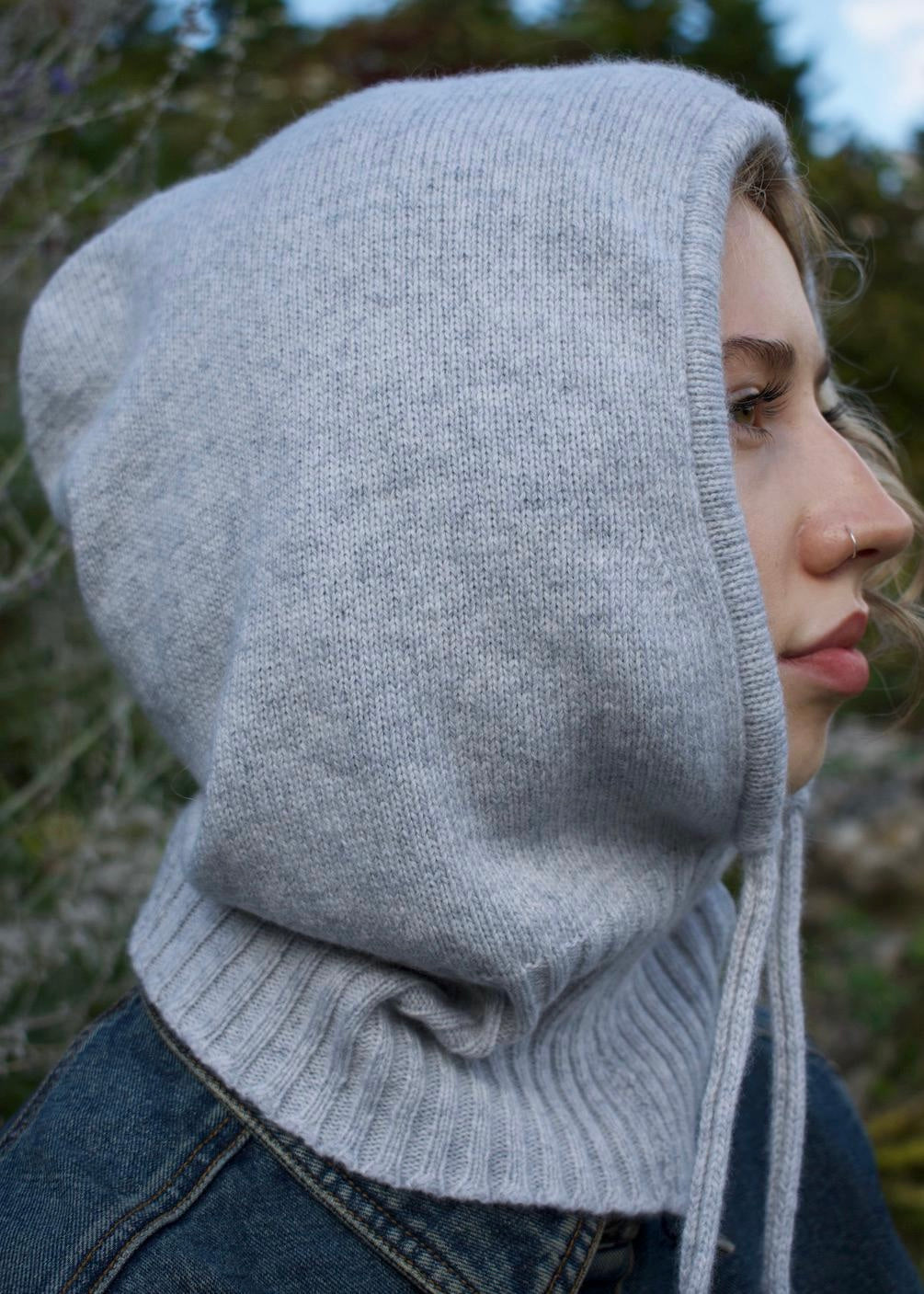 Our grey cashmere knitted balaclava hood pictured on as woman from a side view outdoors 