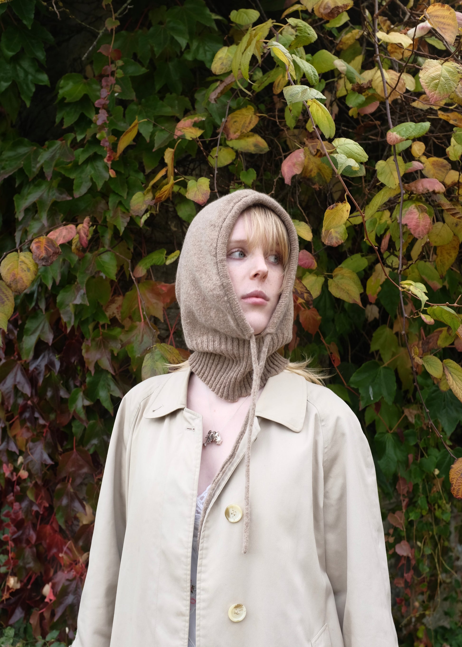 Our cashmere knitted balaclava hood in tan pictured on a woman outdoors 