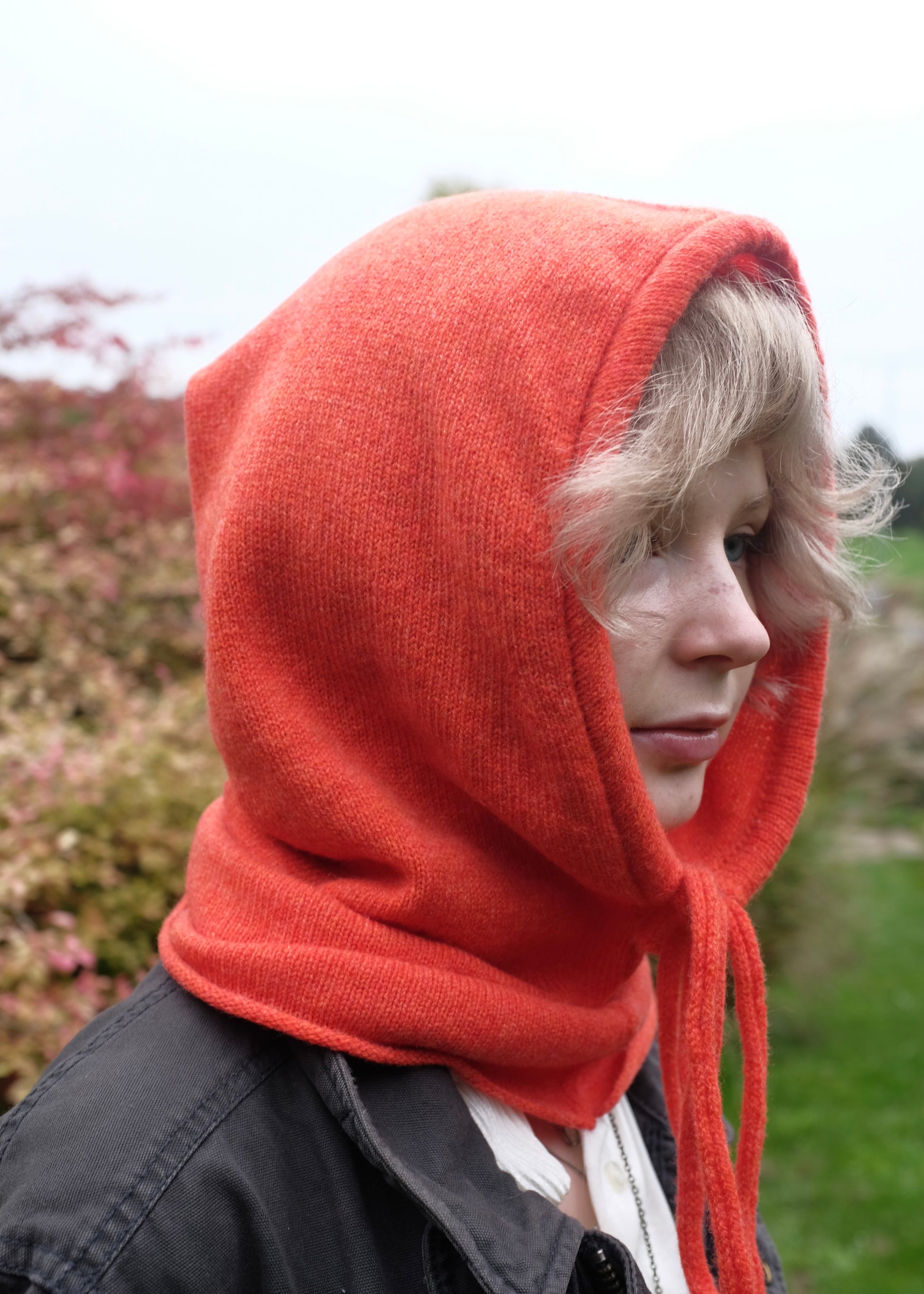 Our cashmere knitted balaclava hood in orange pictured on a woman outdoors 