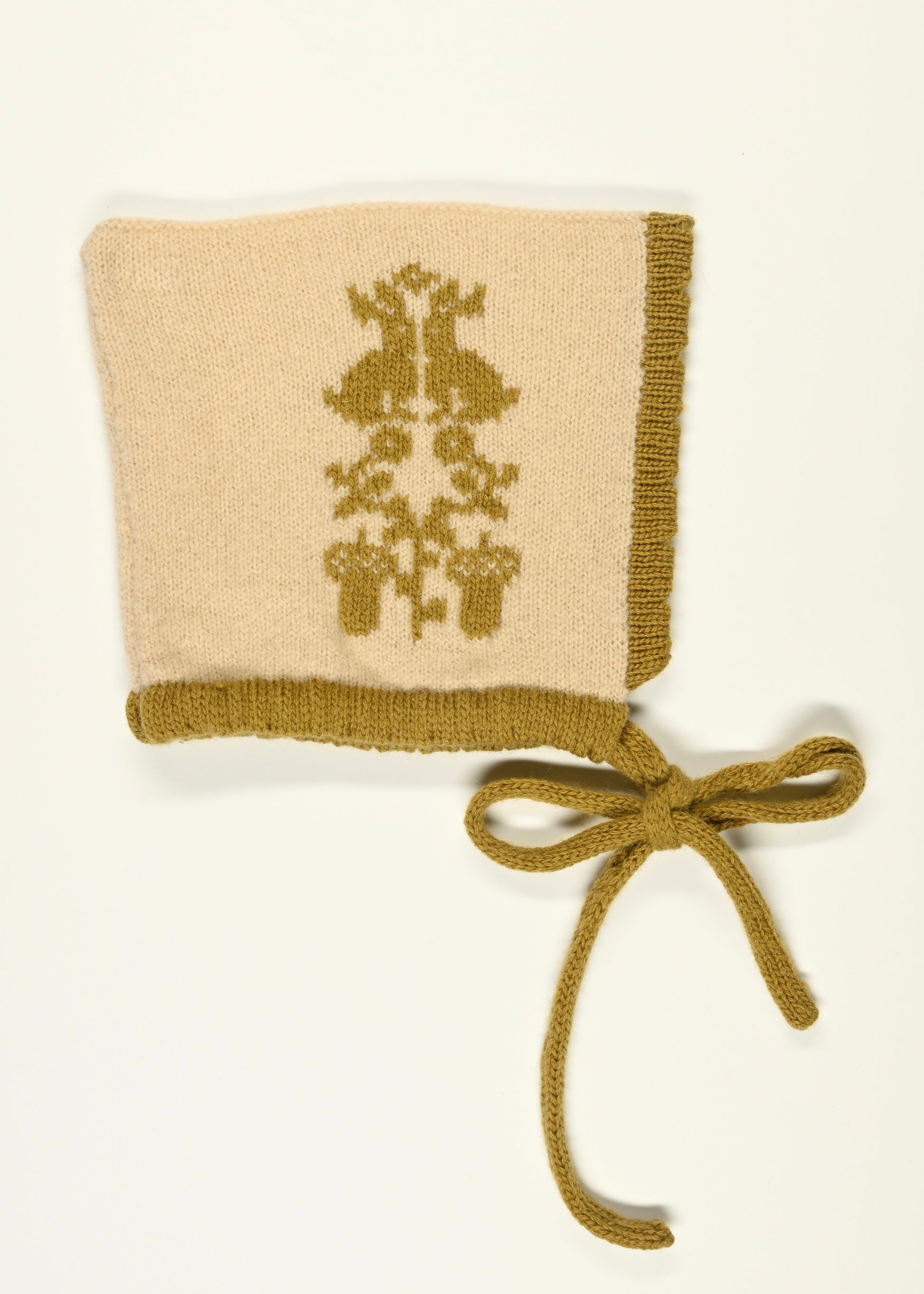 Knitted baby bonnet with golden floral animal pattern and tied ribbon on a white background