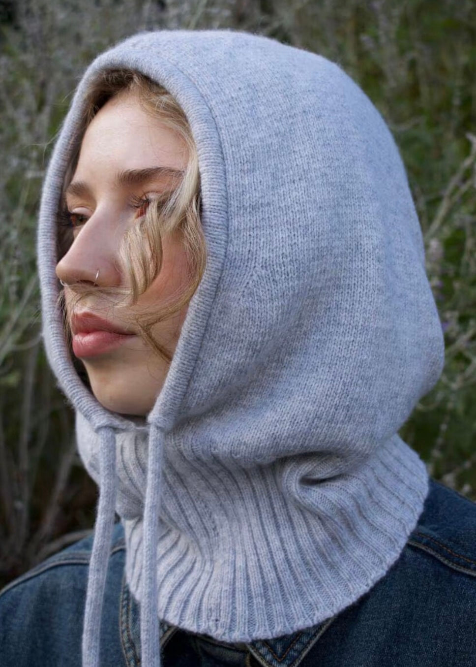 Our cashmere knitted balaclava hood in grey pictured on a woman outdoors 