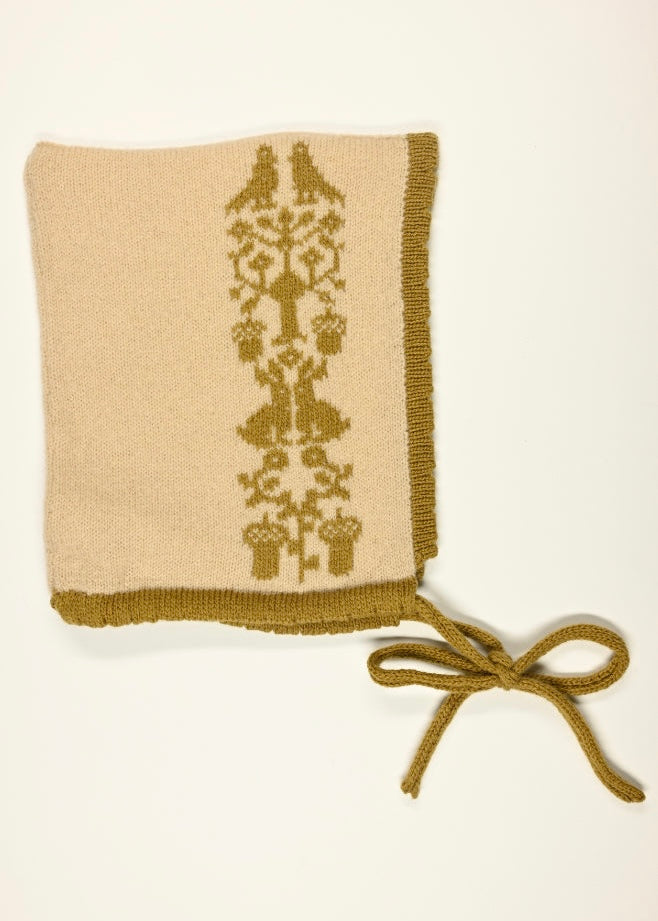 Knitted bonnet with a golden animal and floral pattern  on a white background