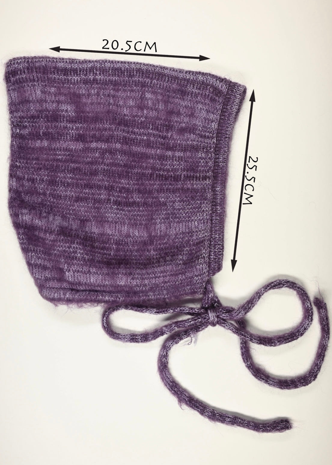 Purple knitted bonnet with measurements (20.5cm wide by 25.5cm long) on a white background