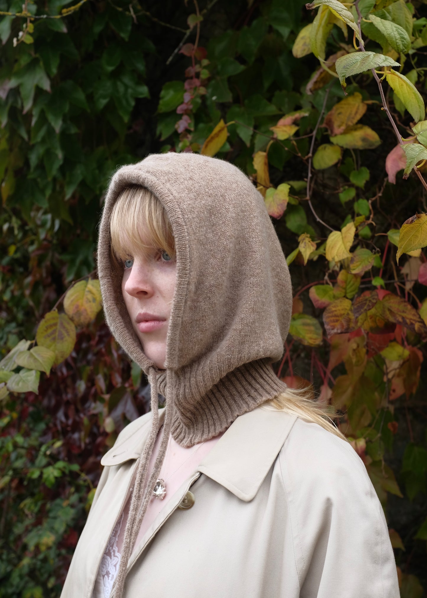 Our cashmere knitted hood balaclava in tan pictured on a woman outdoors 