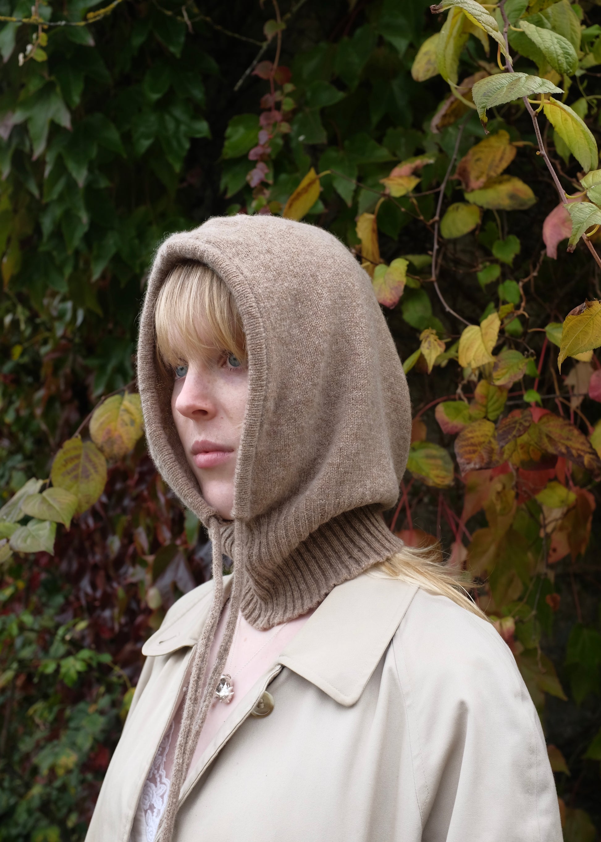 Our cashmere knitted hood balaclava in tan pictured on a woman outdoors 