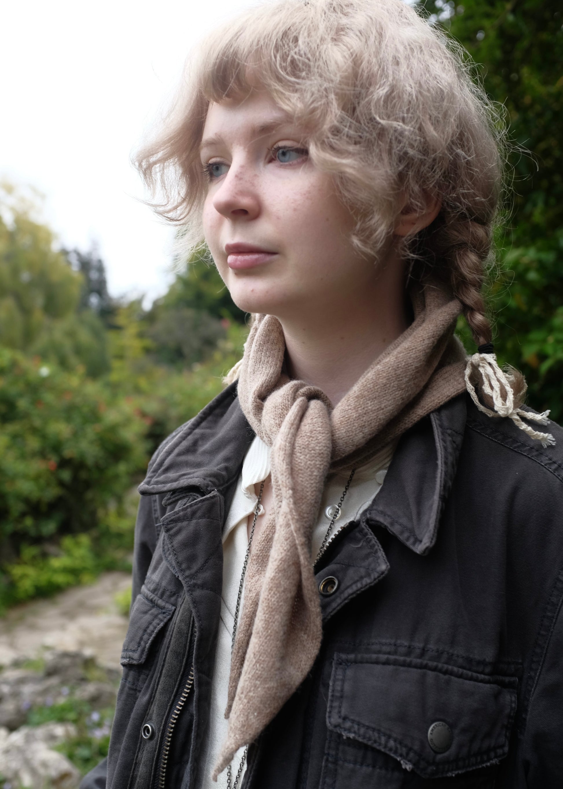 Woman with braided hair wearing a scarf and jacket outdoors