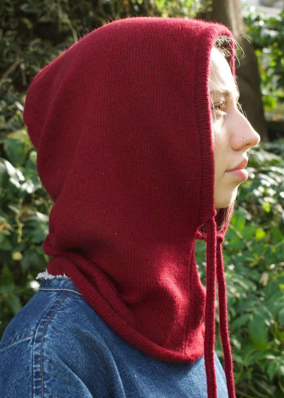 Our cashmere knitted balaclava hood in burgundy pictured on a woman from a side angel 