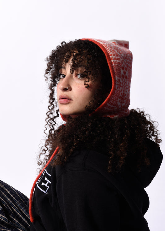 Person wearing a black hoodie with a  orange bonnet hood against a white background