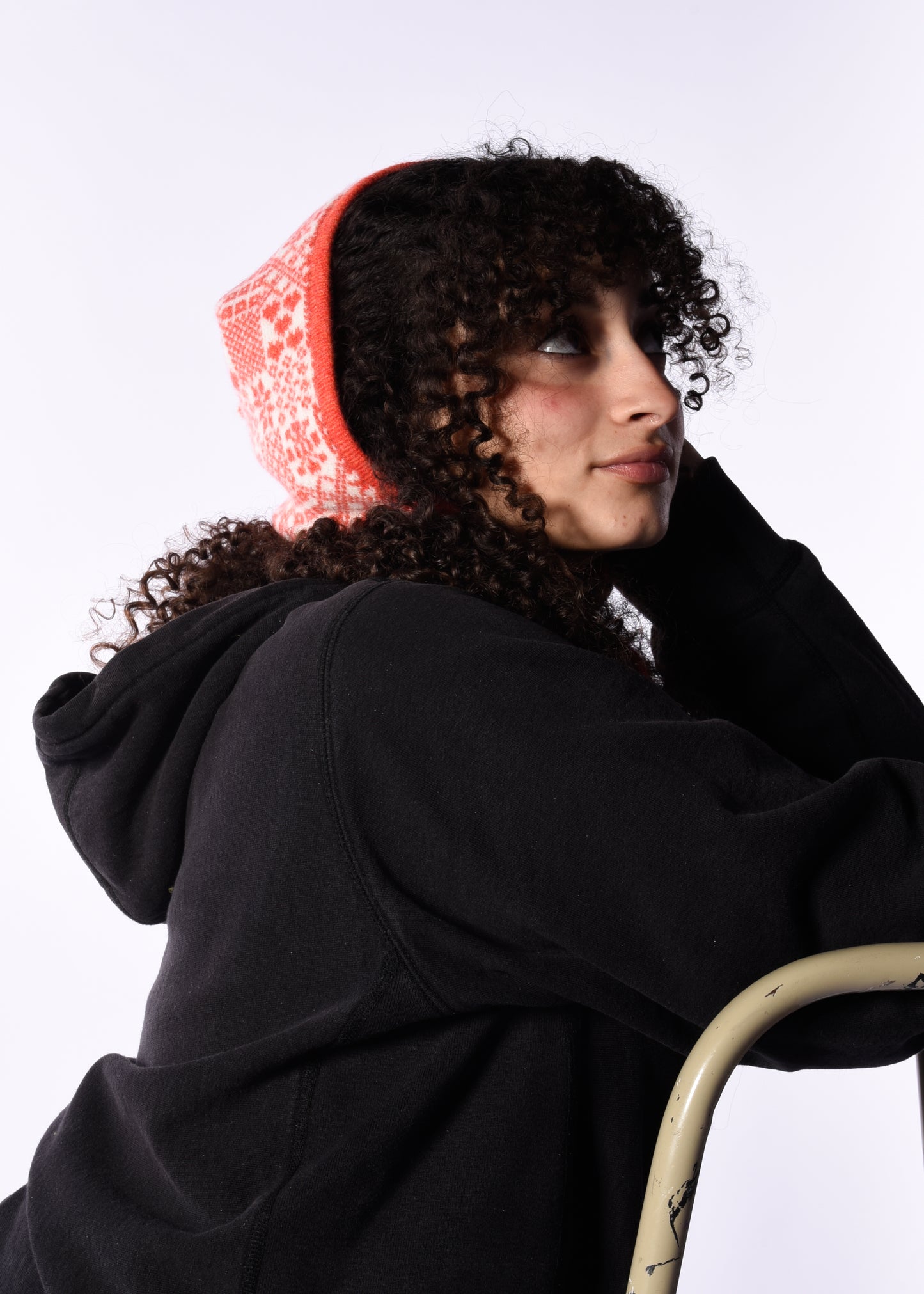 Person wearing a black hoodie and orange hood against a white background