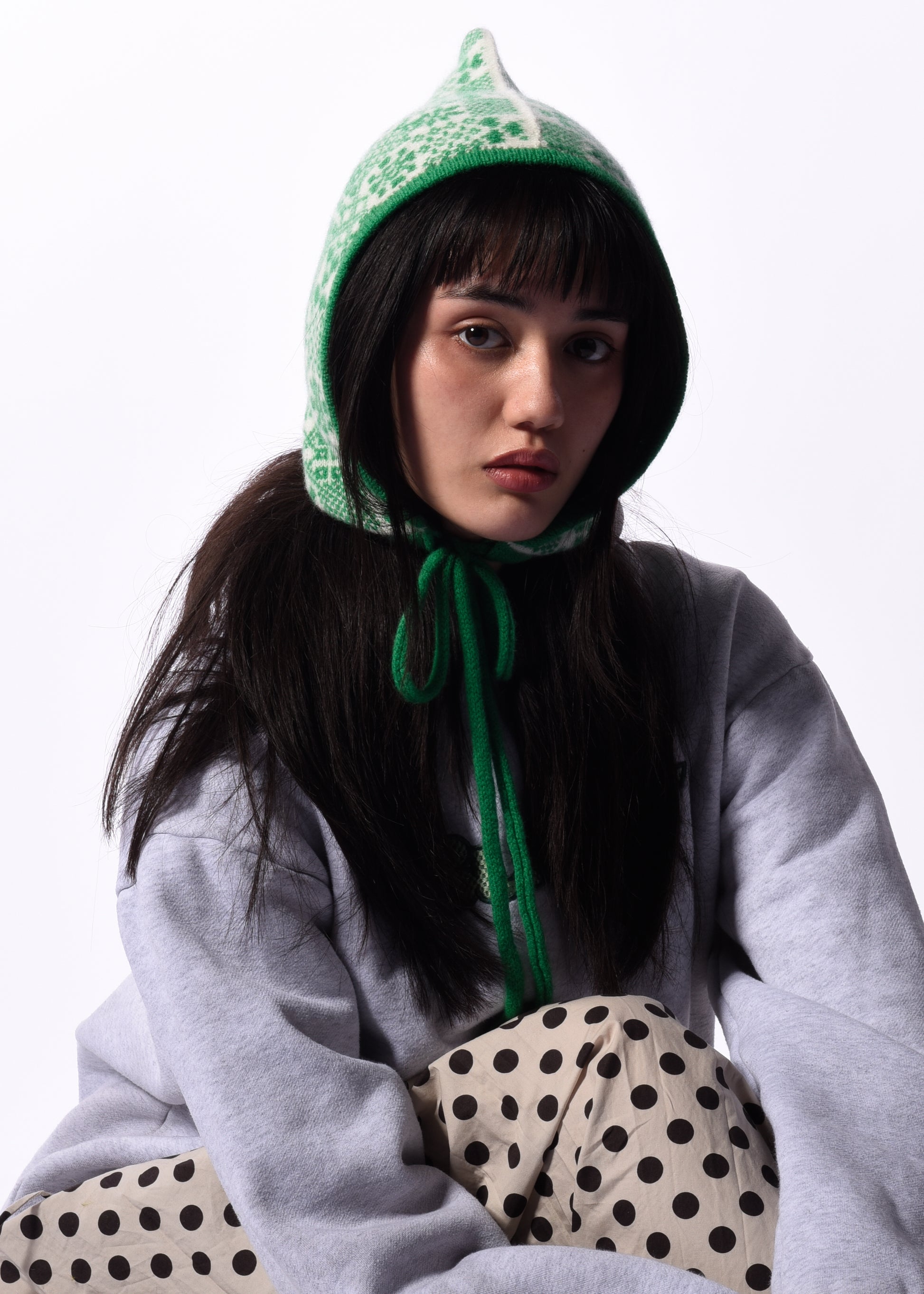 Person wearing a green hooded bonnet with a white background