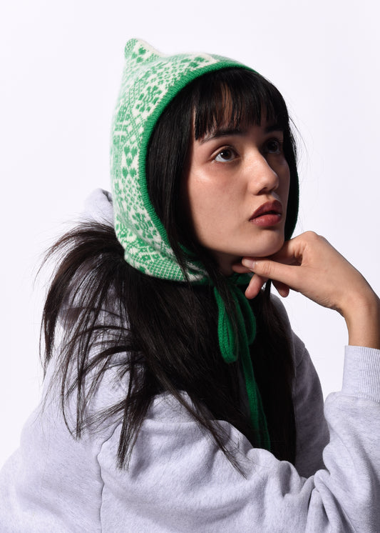 Person wearing a green patterned Bonnet on a white background