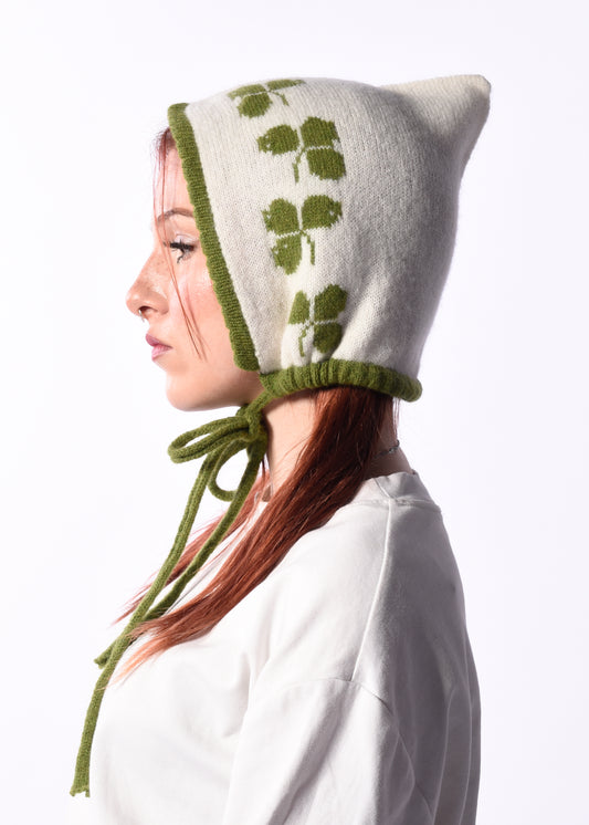 woman wearing a cream bonnet with green trim and Irish shamrock motif