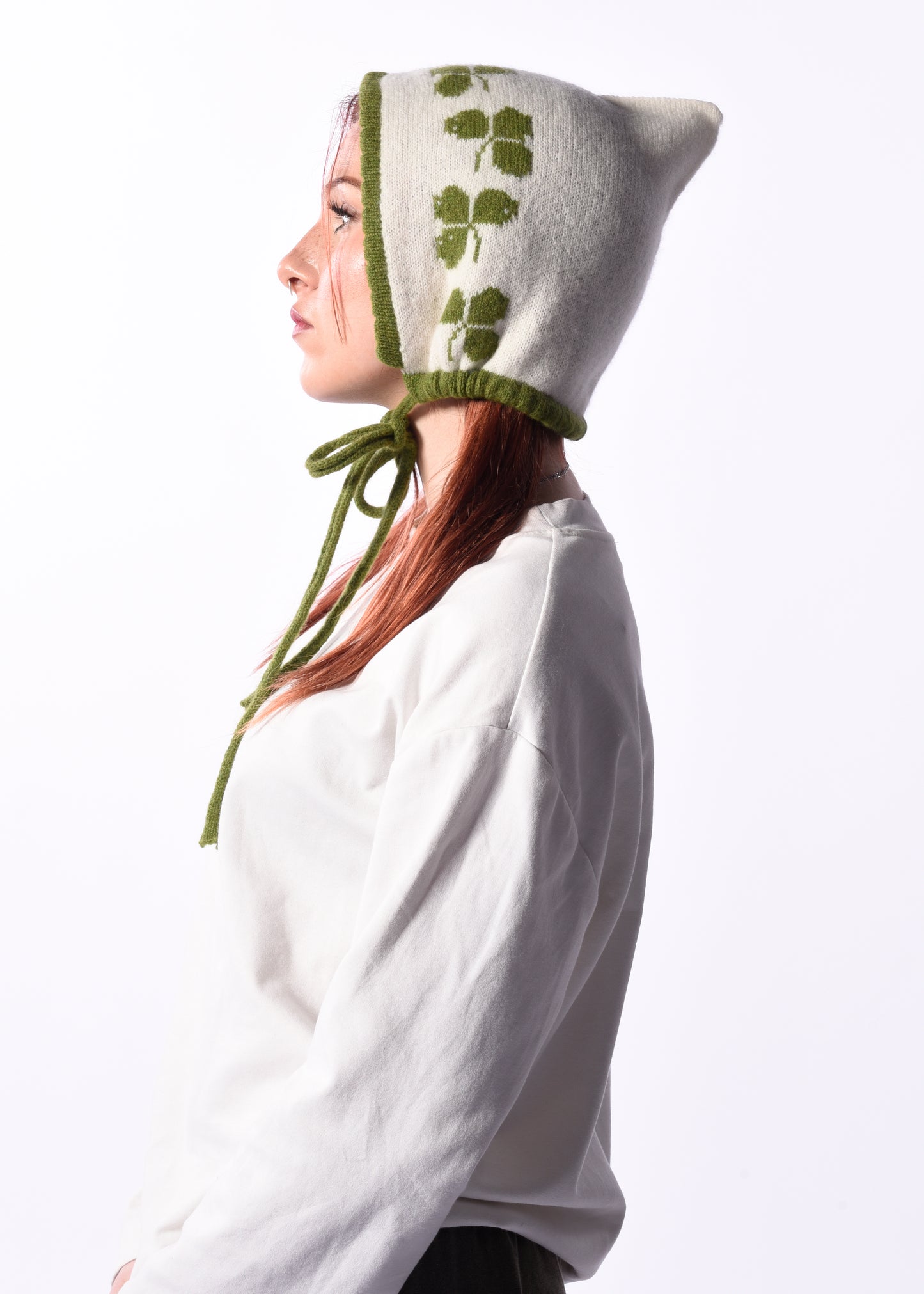 Person wearing a white hood with green trim and leaf patterns on a white background