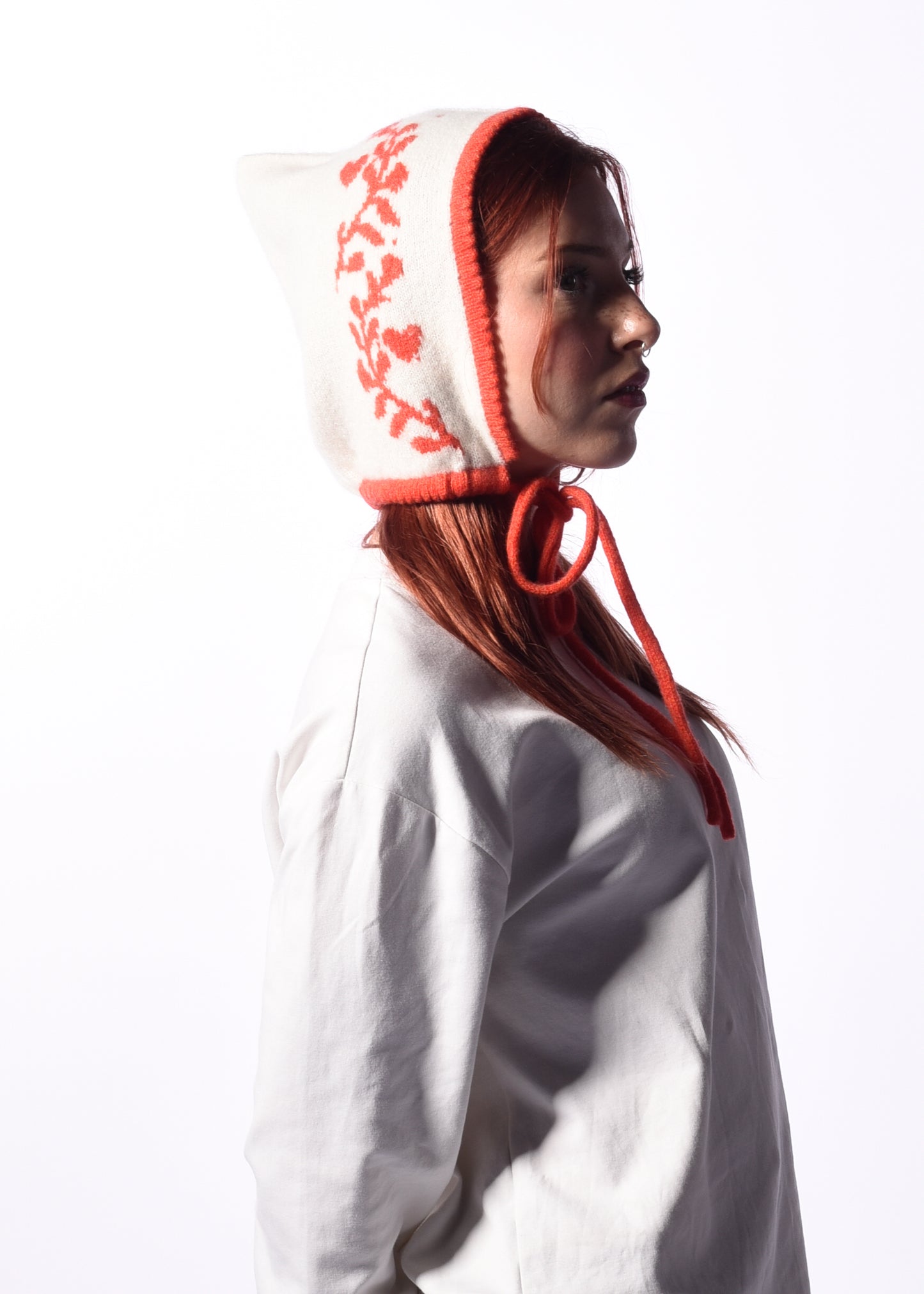 Person wearing a white hood with orange trim on a white background