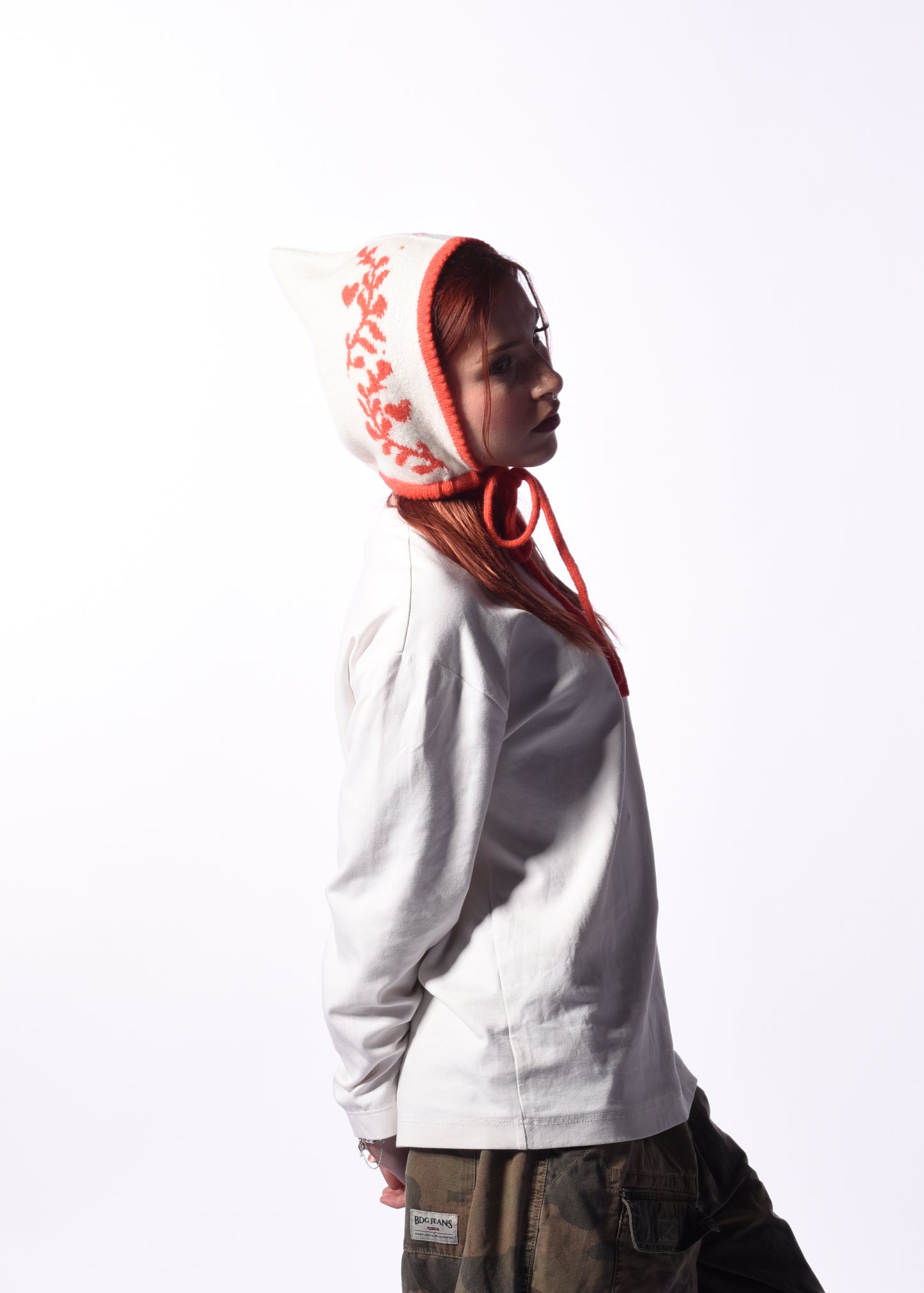 Person wearing a white hoodie with a white and orange hood and floral patterns on a white background