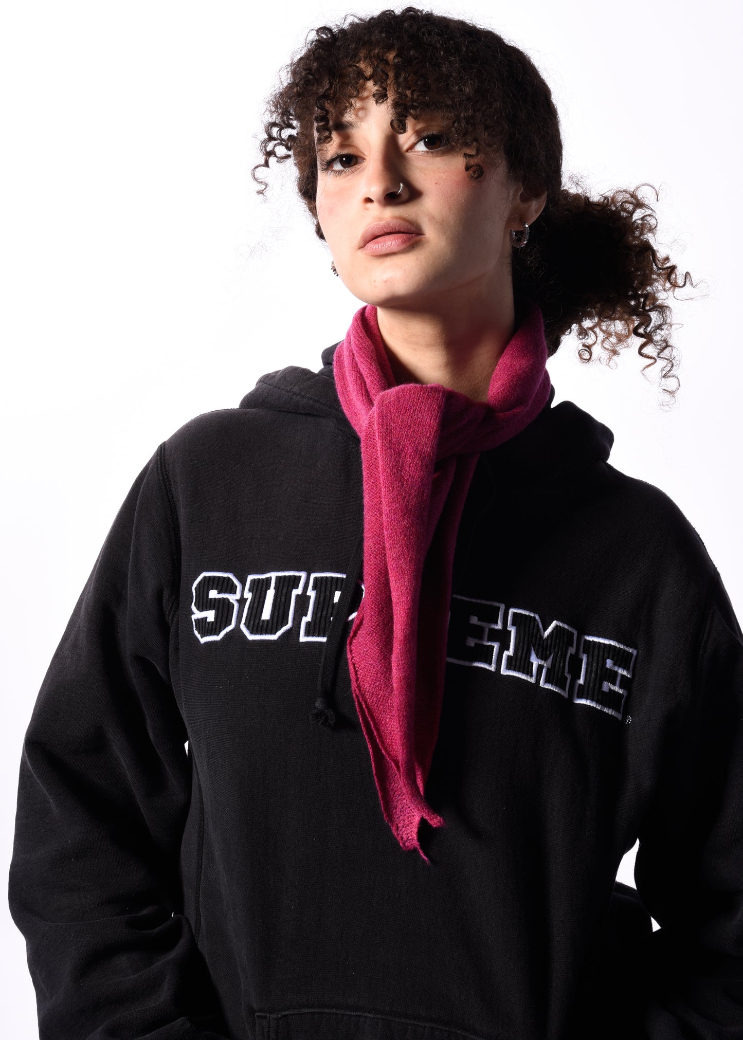 a woman wearing a pink knitted neckerchief in front of a white background