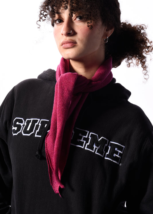 a woman wearing a pink knitted neckerchief in front of a white background