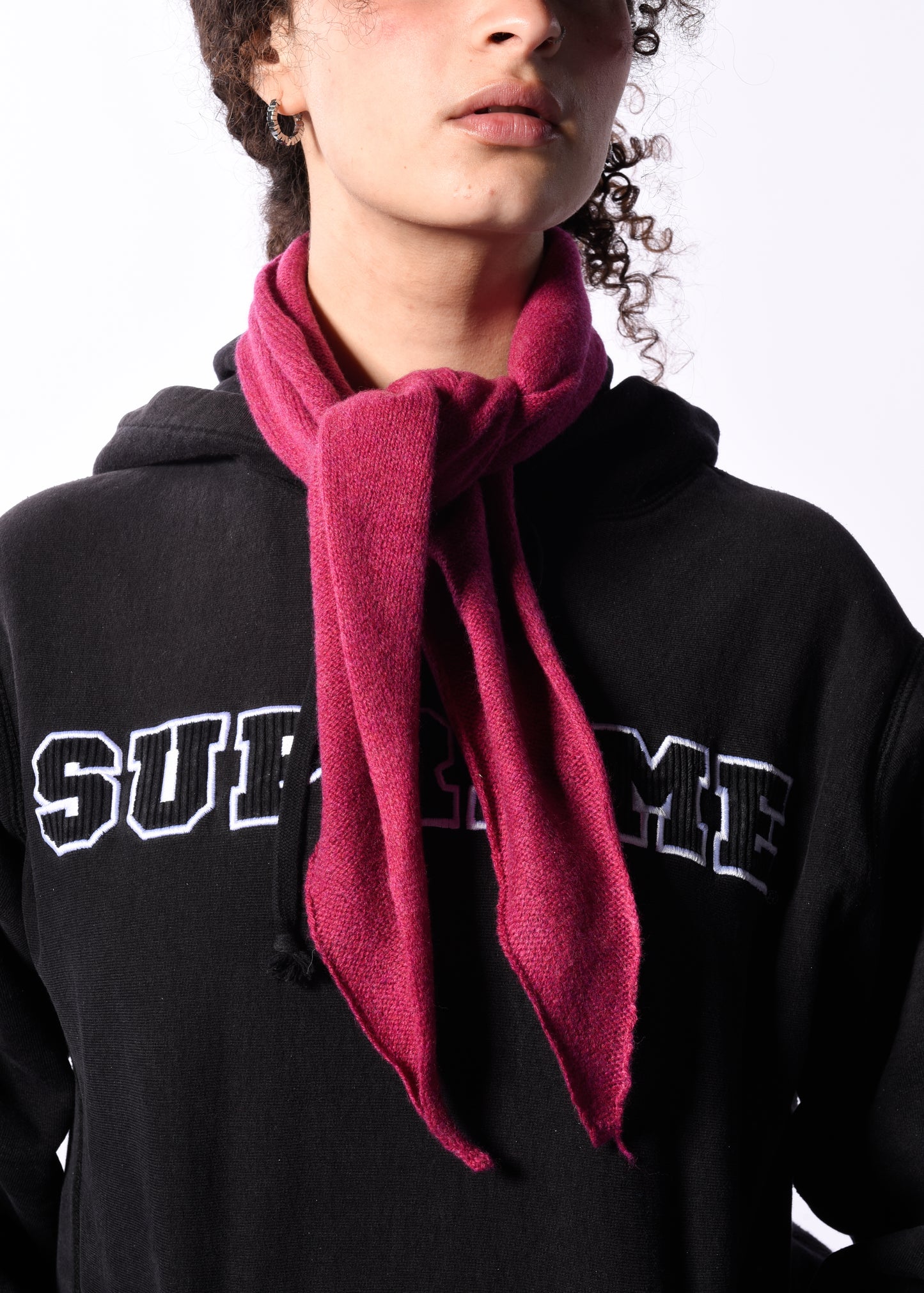 Person wearing a black Supreme hoodie with a pink scarf