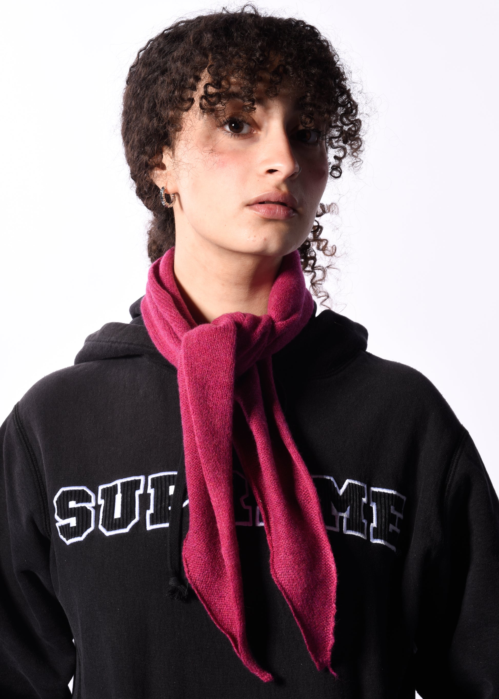 Person wearing a black hoodie with 'Supreme' branding and a pink scarf.