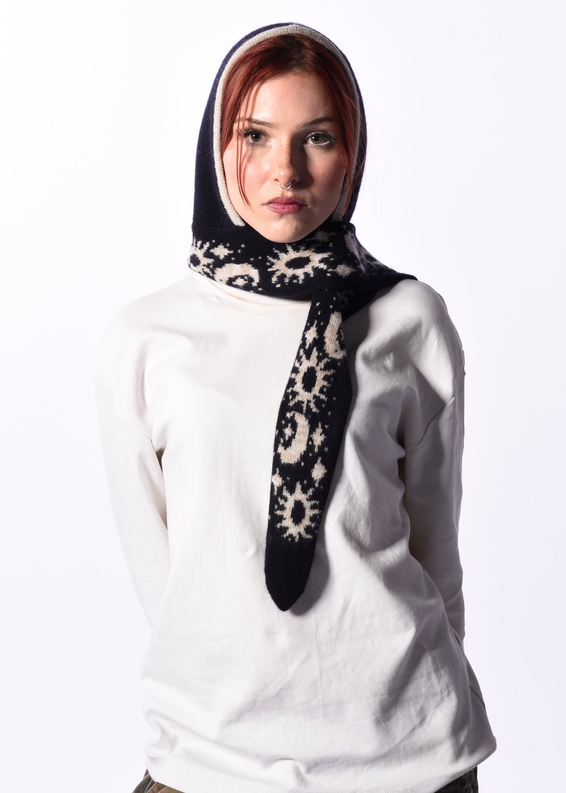 Woman wearing a white top and a patterned hooded scarf bonnet on a white background