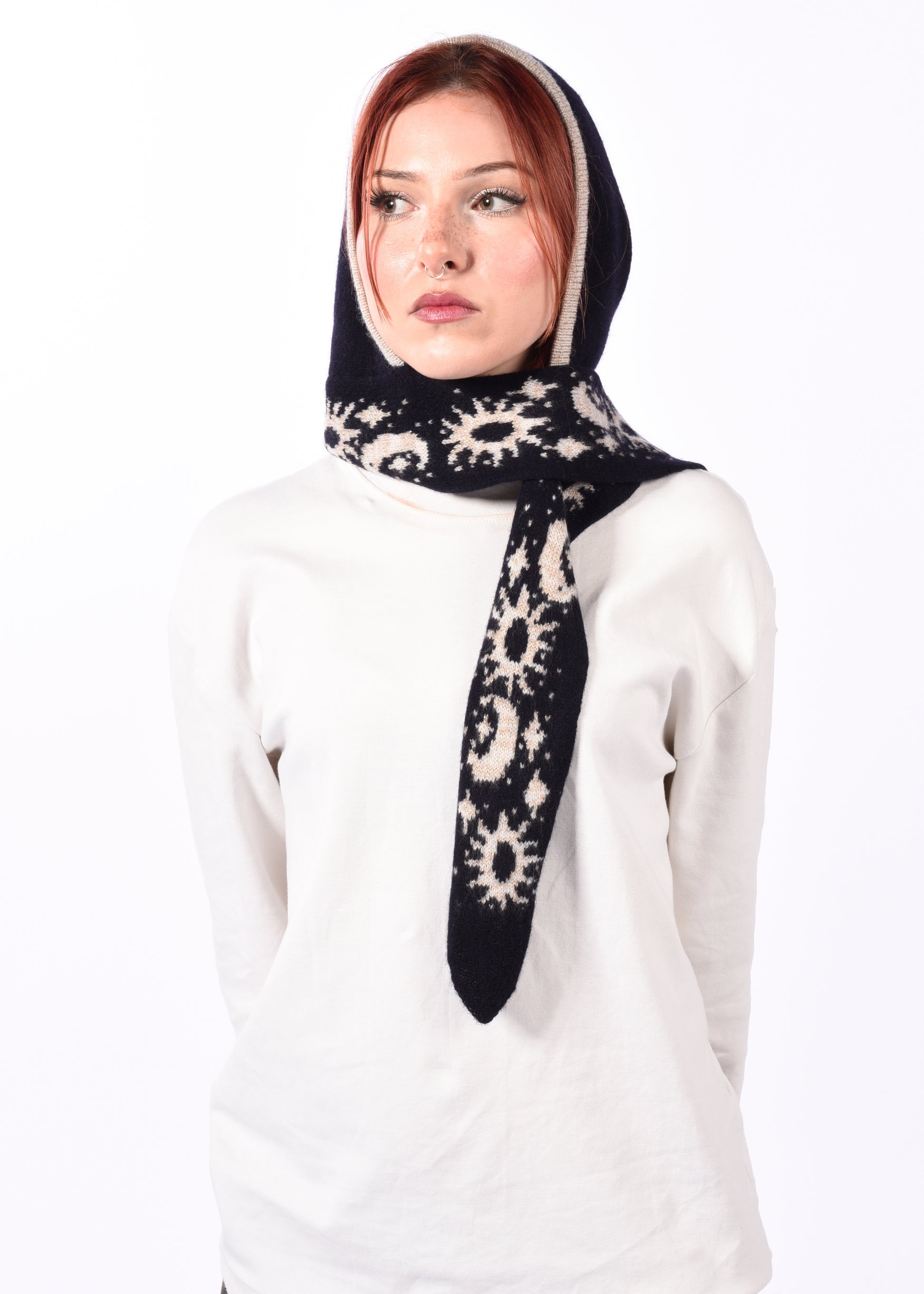 Woman wearing a navy and white patterned scarf bonnet on a white background