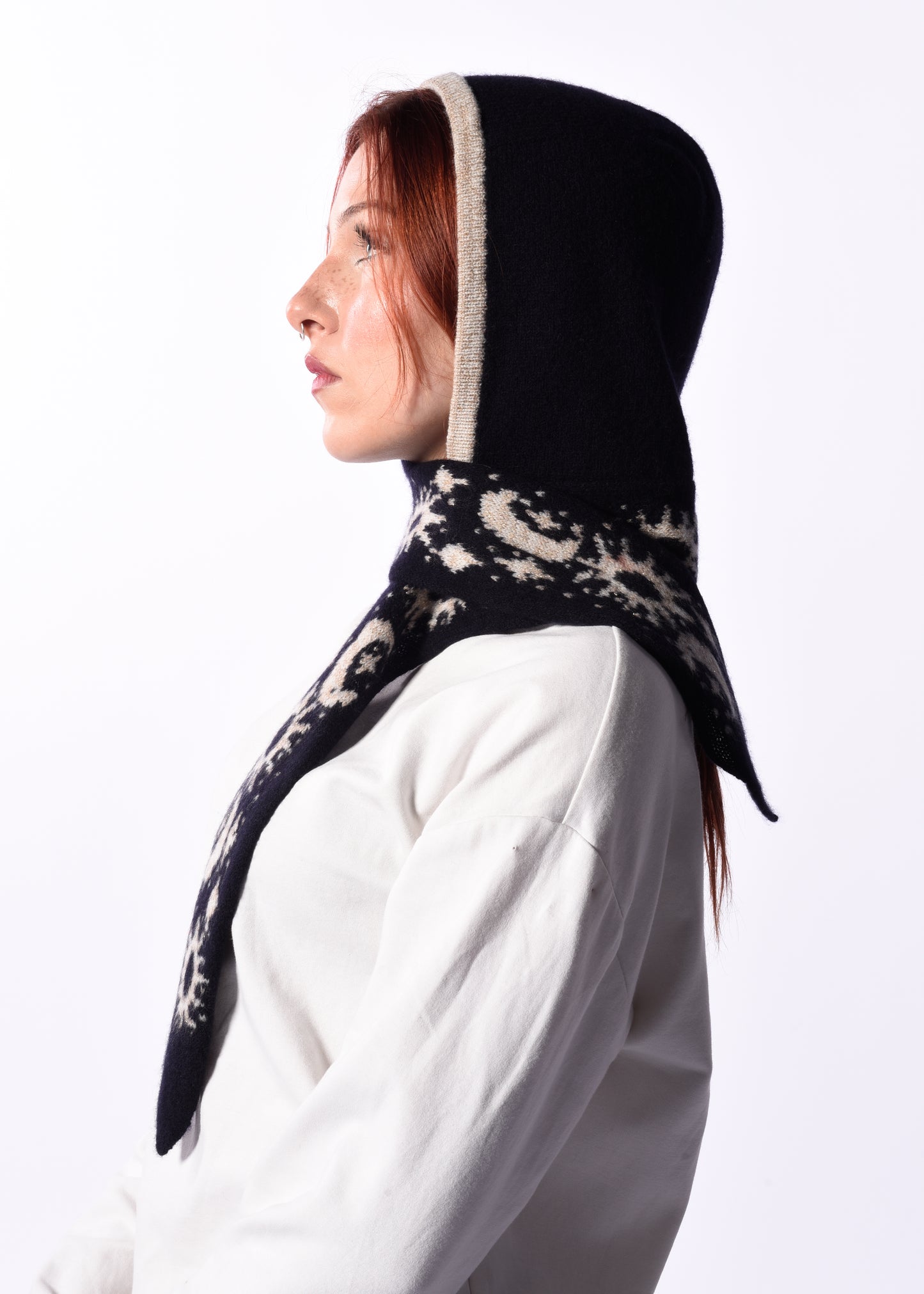 Woman wearing a navy scarf bonnet with white patterns on a white background