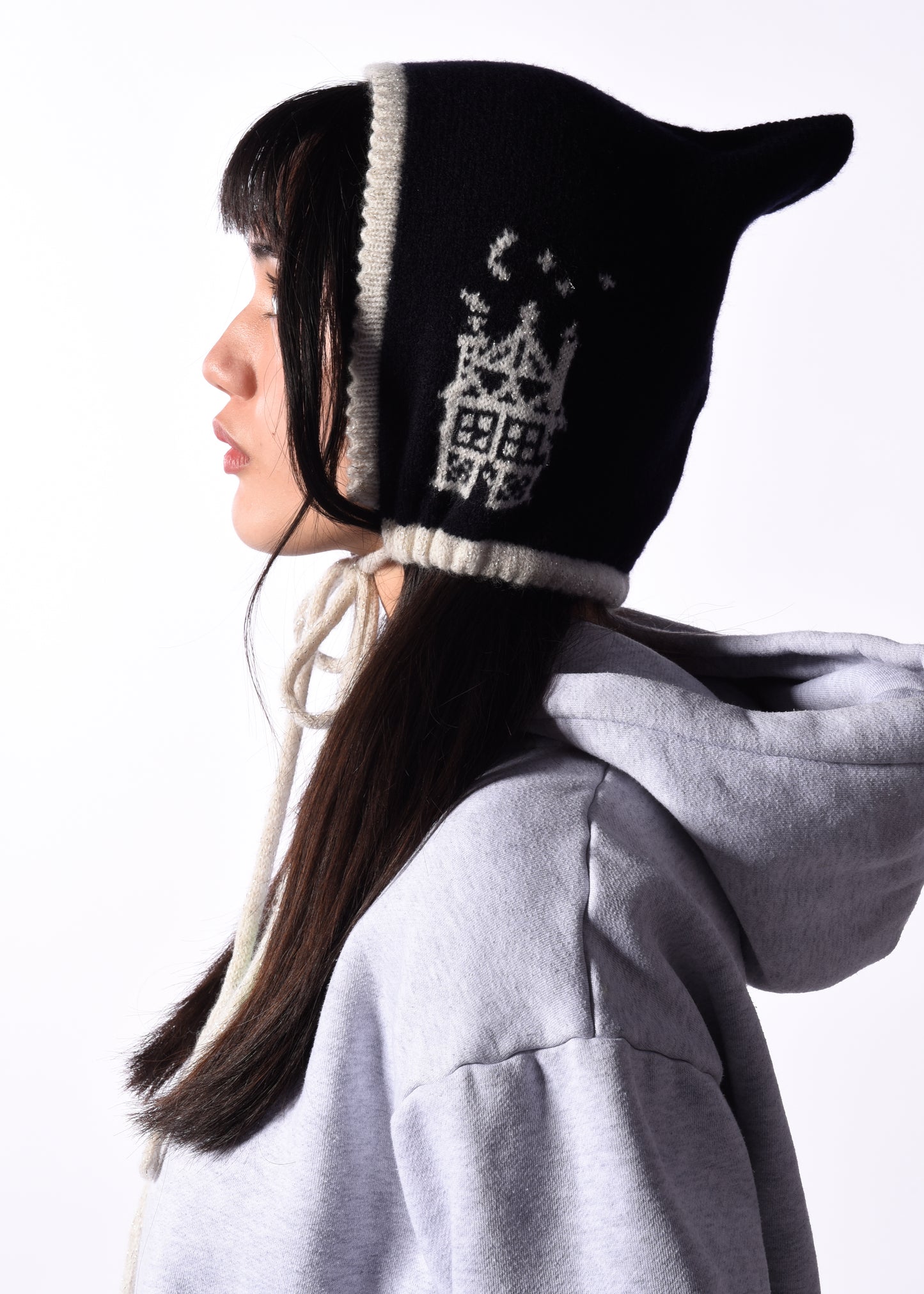 Person wearing a navy and white knitted hat with a pattern, against a white background
