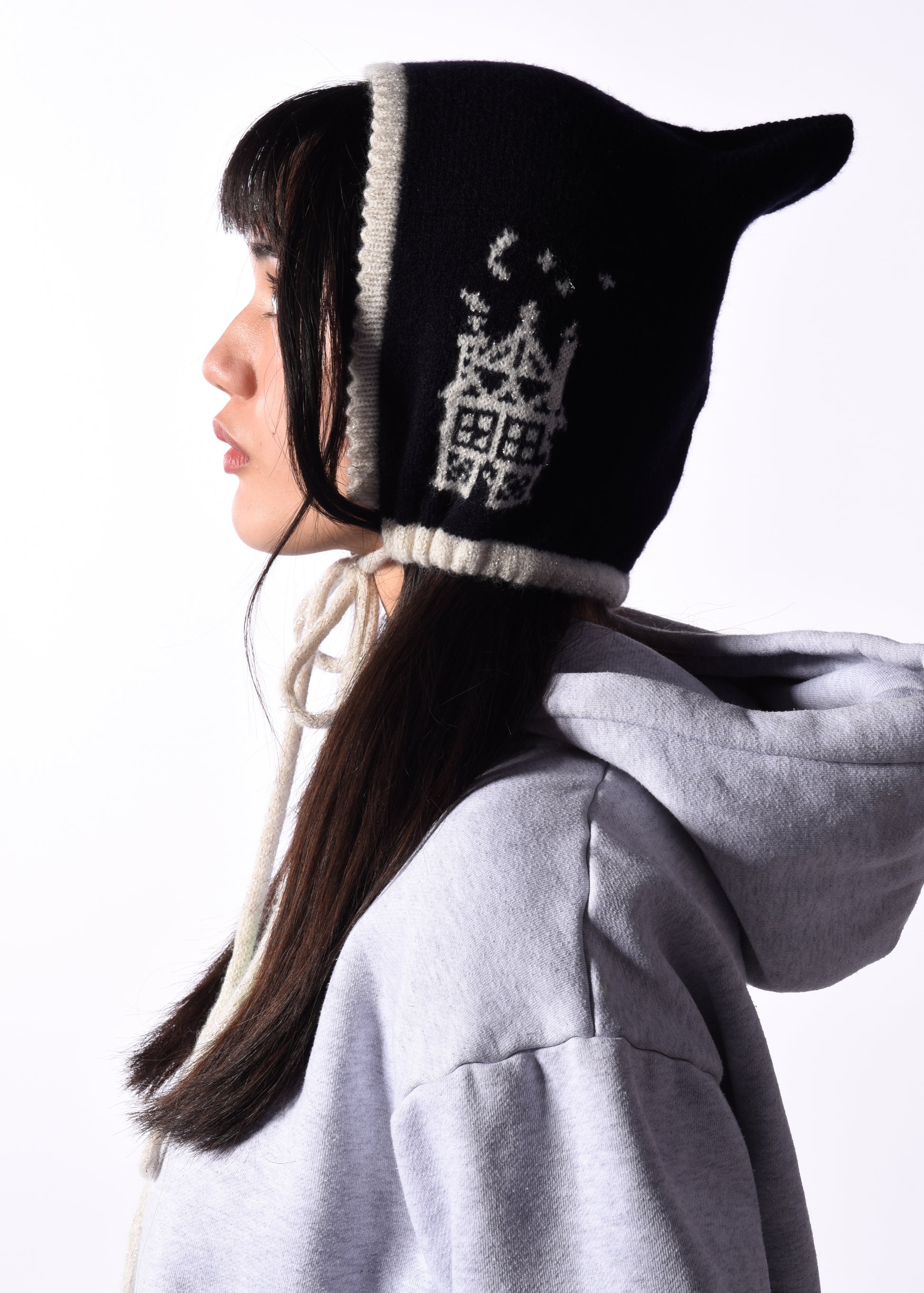 Person wearing a navy and white knitted hat with a pattern, against a white background