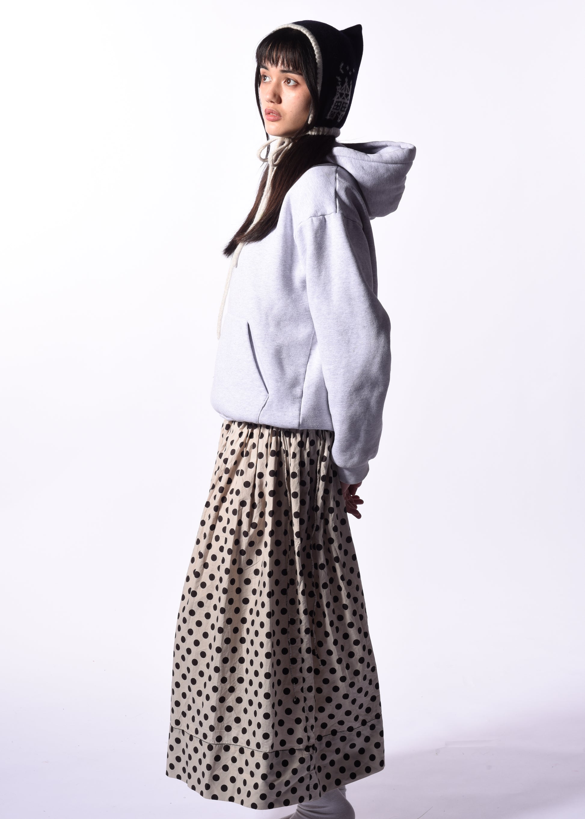 Person wearing a white hoodie and polka dot skirt on a white background
