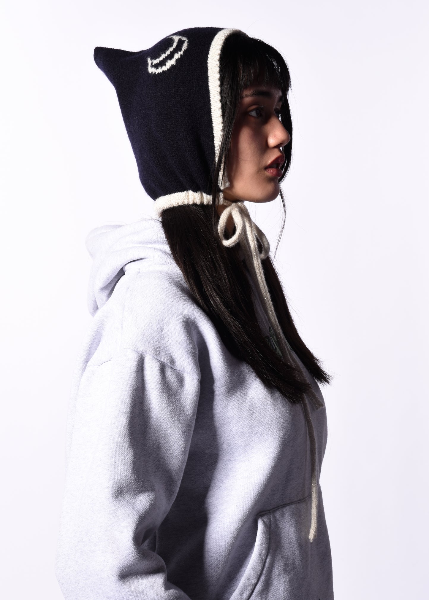 Person wearing a black and white hooded garment with a cat-like design on a white background