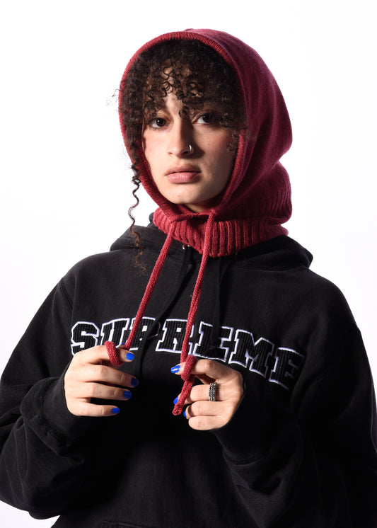 a woman wearing a dark pink balaclava in front of a white background