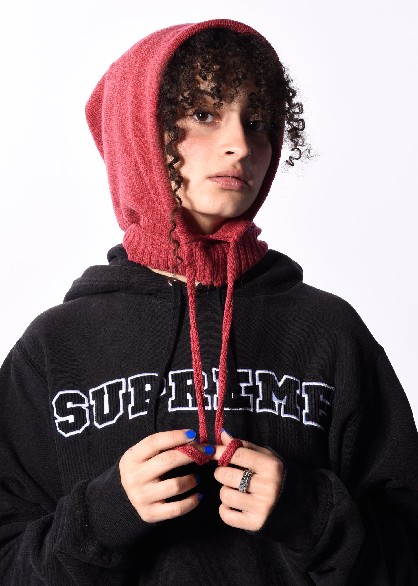 a woman wearing a dark pink balaclava in front of a white background