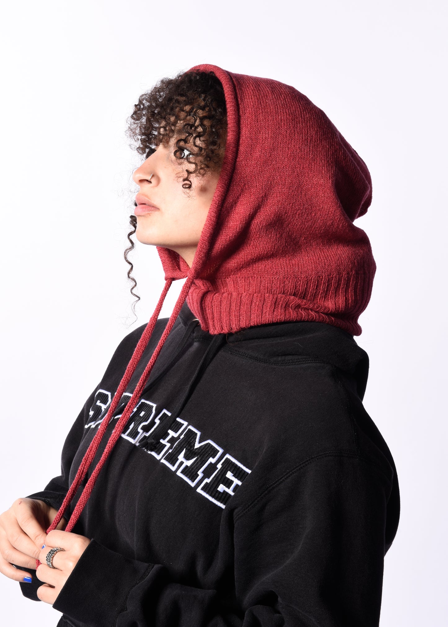 Person wearing a black hoodie with a dark pink hood hood against a white background