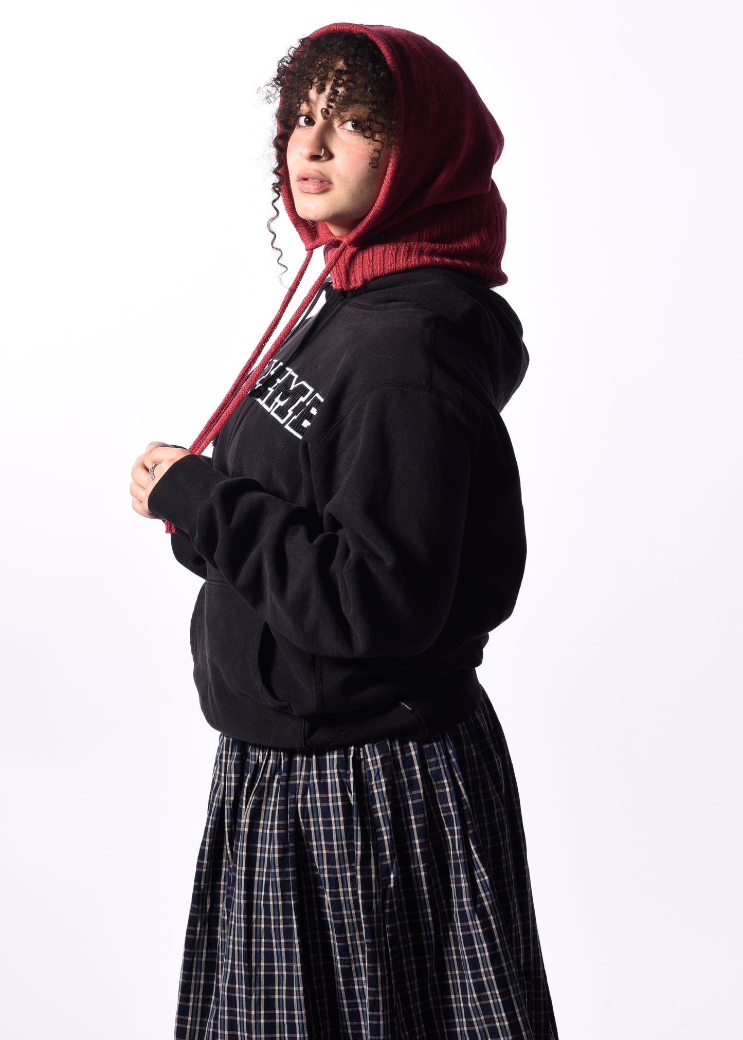 a woman wearing a dark pink balaclava in front of a white background
