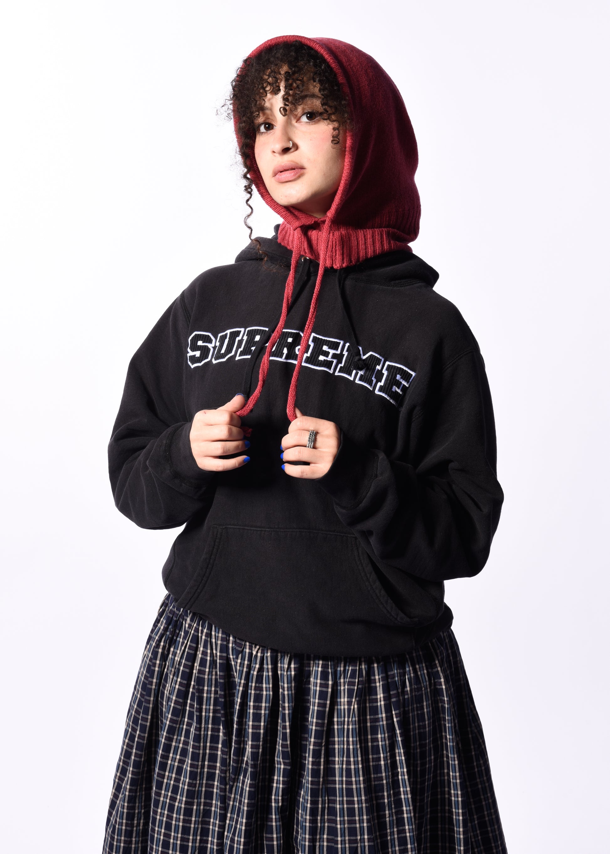 a woman wearing a dark pink balaclava in front of a white background