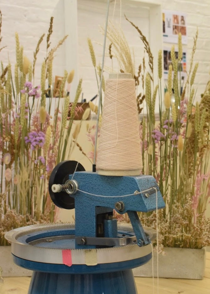 Spinning wheel with yarn on a blurred floral background