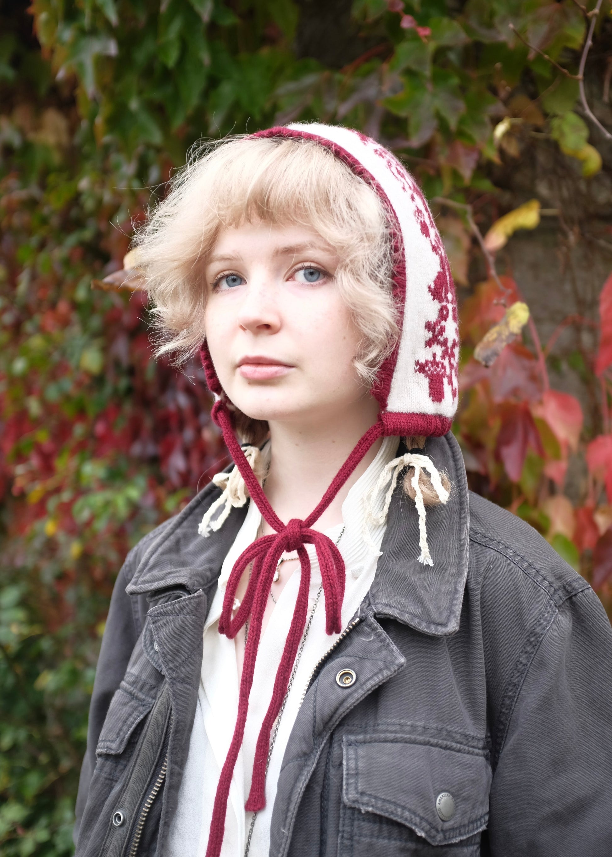Person wearing a patterned bonnet in front of a leafy background