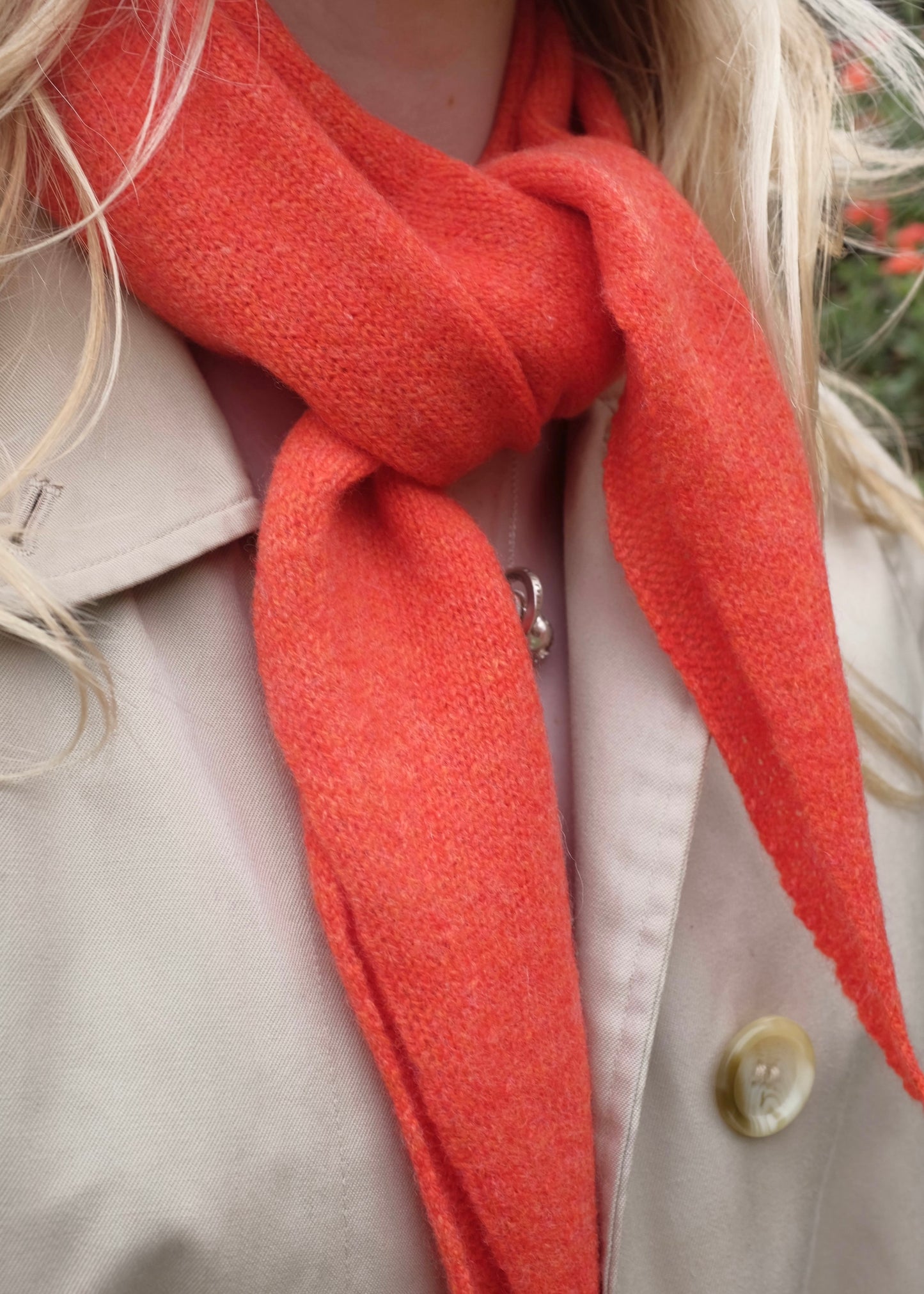 A close up of a neck wearing our orange cashmere knitted “Sophie style” scarf tied neatly around her neck 