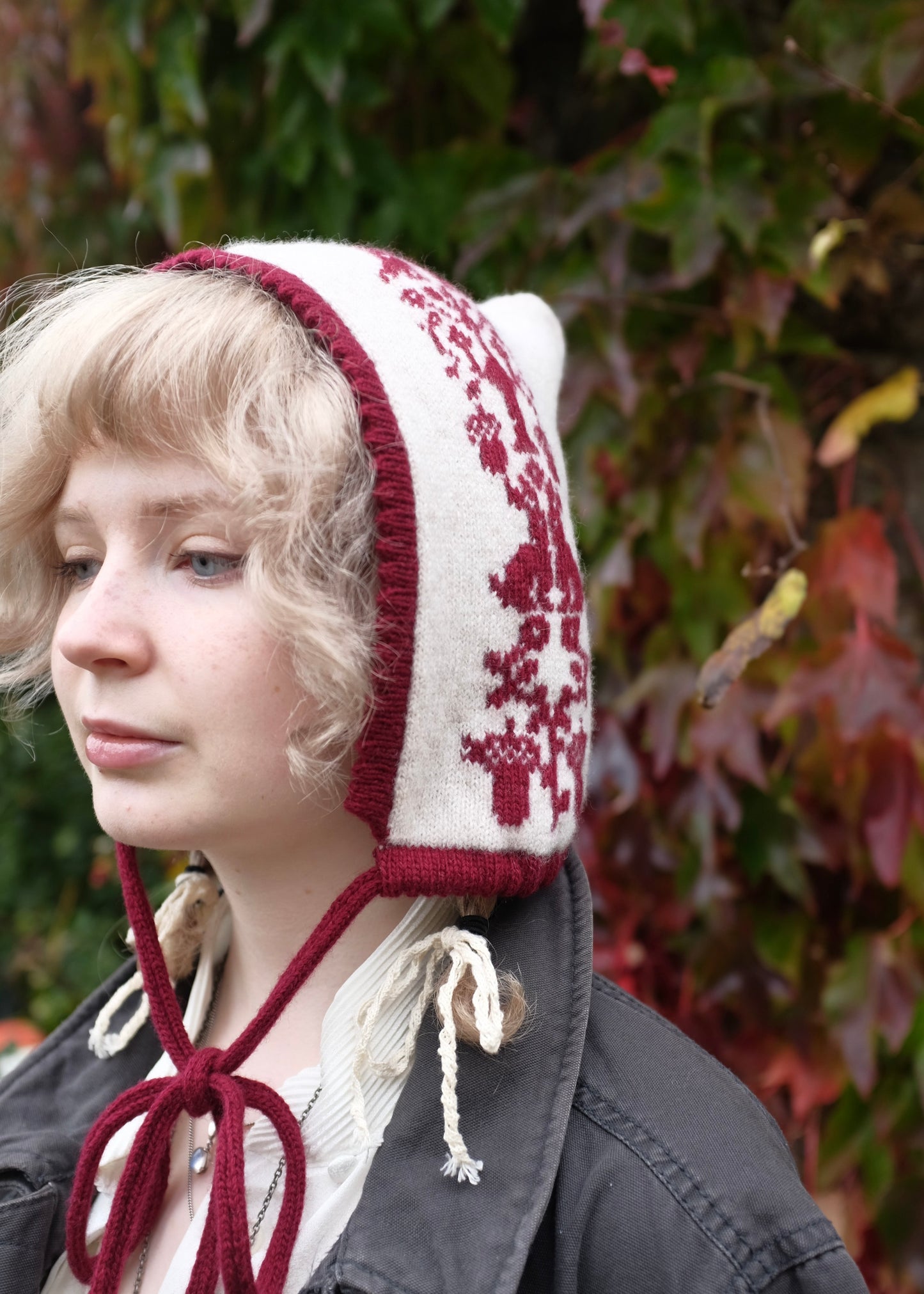 Person wearing a red and white patterned bonnet against a leafy background