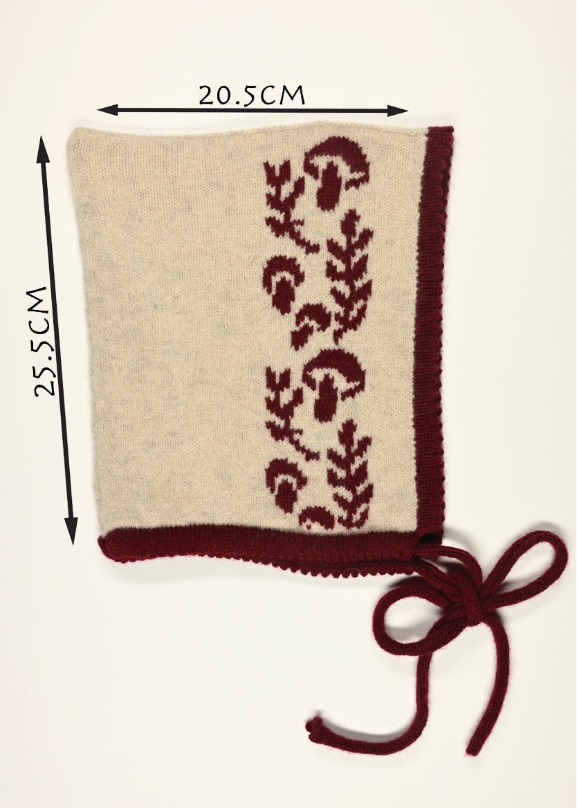 Knitted product with burgundy  floral mushroom pattern, trim and tie with a cream base and dimensions on a white background. 25.5cm long by 20.5cm wide 