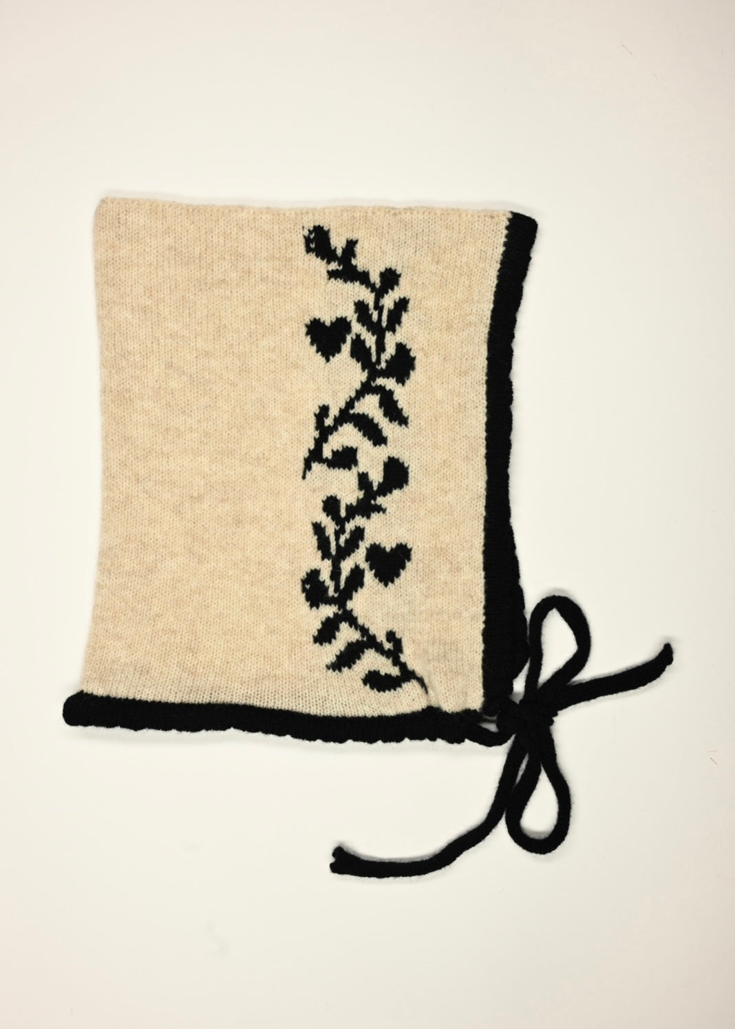 A flat lay of our cashmere knitted in cream with a lack trim, tie and laurel lead design 