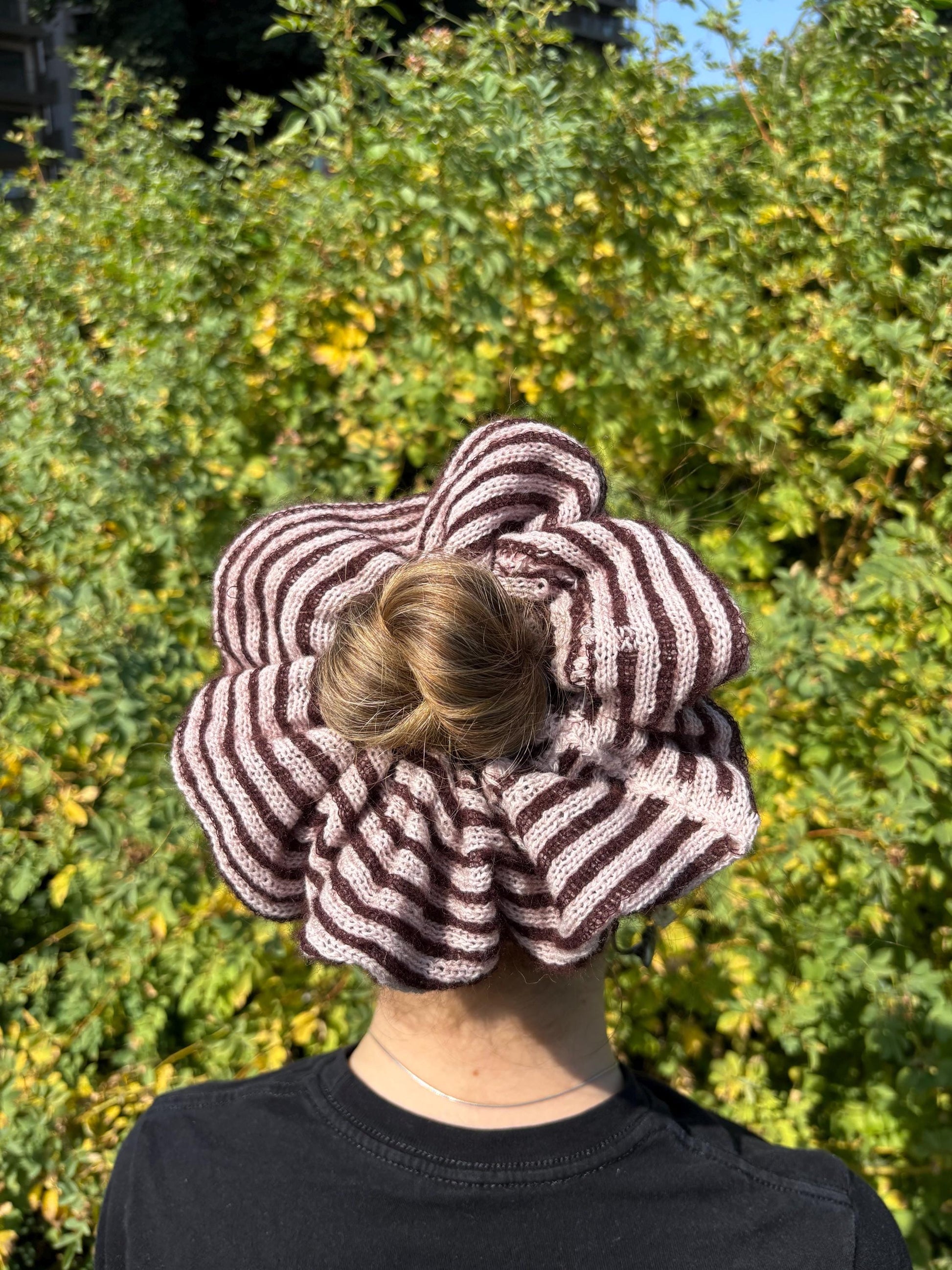 Back view of a women wearing a plum and pink striped mohair-cashmere oversized scrunchie, set against a grassy backdrop 