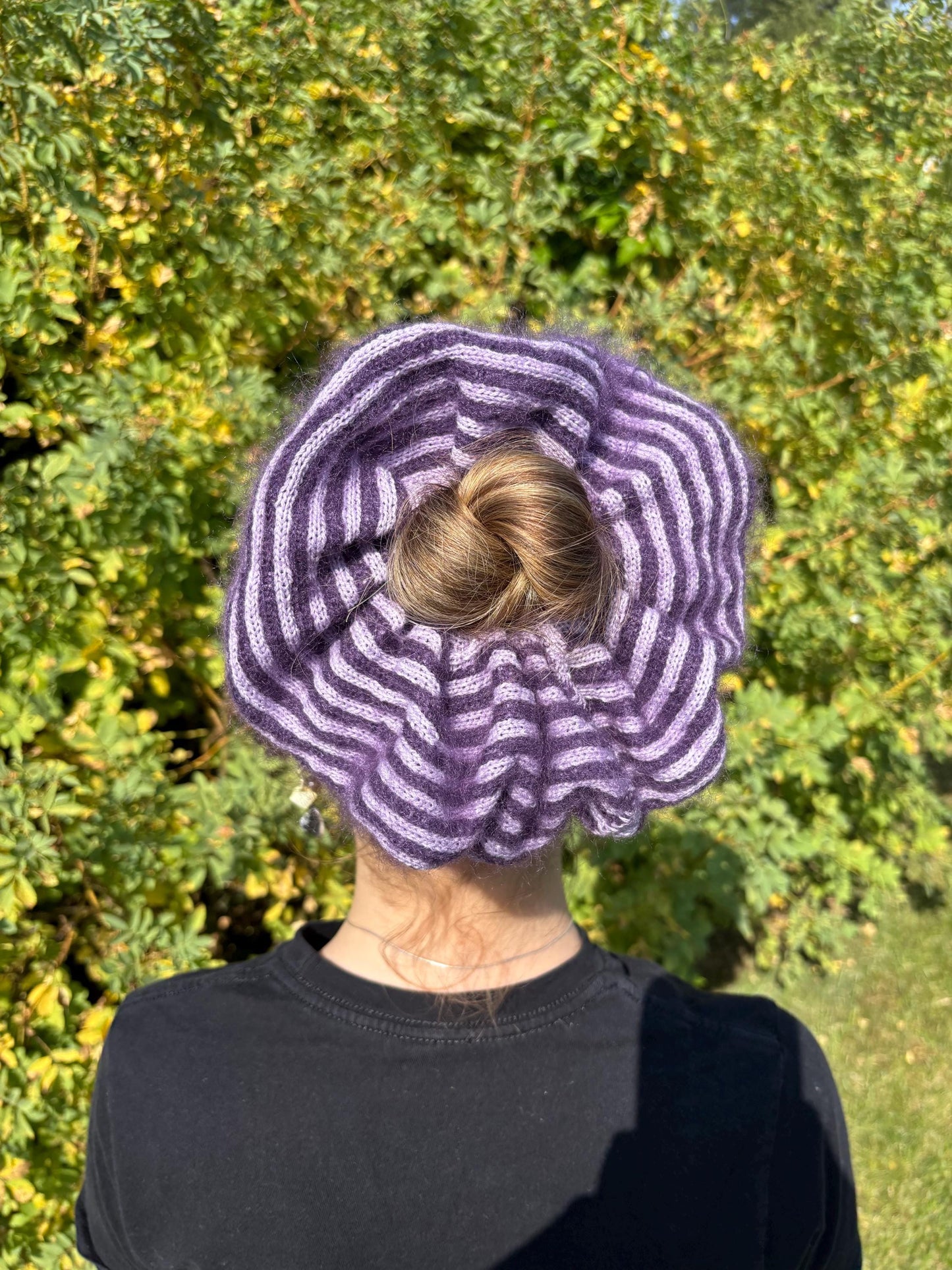 Back view of a women wearing a purple and white striped mohair-cashmere oversized scrunchie, set against a grassy backdrop 